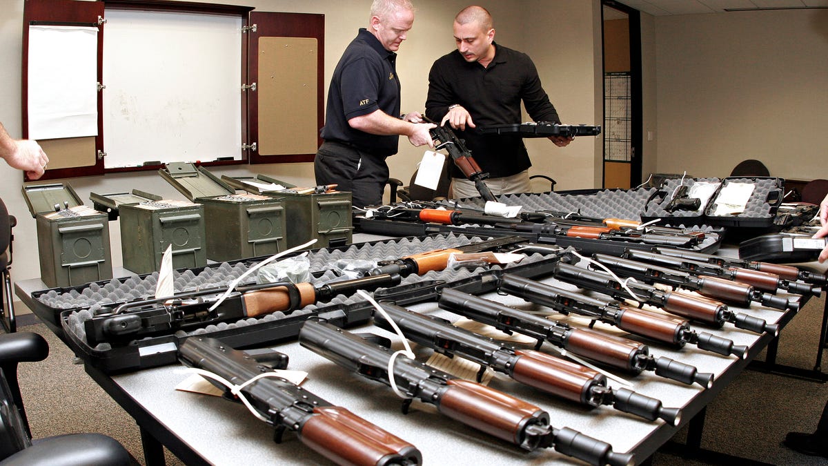 Phoenix ATF special agents Tom Mangan (L) and Peter Forcelli examine a confiscated AK-47 short pistol at the bureau's headquarters in Phoenix. The guns and the ammunition on the table were part of a shipment bound for Mexico confiscated in 2008.