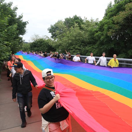 Participants carry a giant pride flag during the Pride in the Sky event at the Walkway Over the Hudson State Historic Park in Poughkeepsie on May 17, 2024. This flag was part of a flag that was used in Key West's pride celebration in 2003 and was 1-1/14 miles long reaching from the Atlantic Ocean to the Gulf of Mexico.