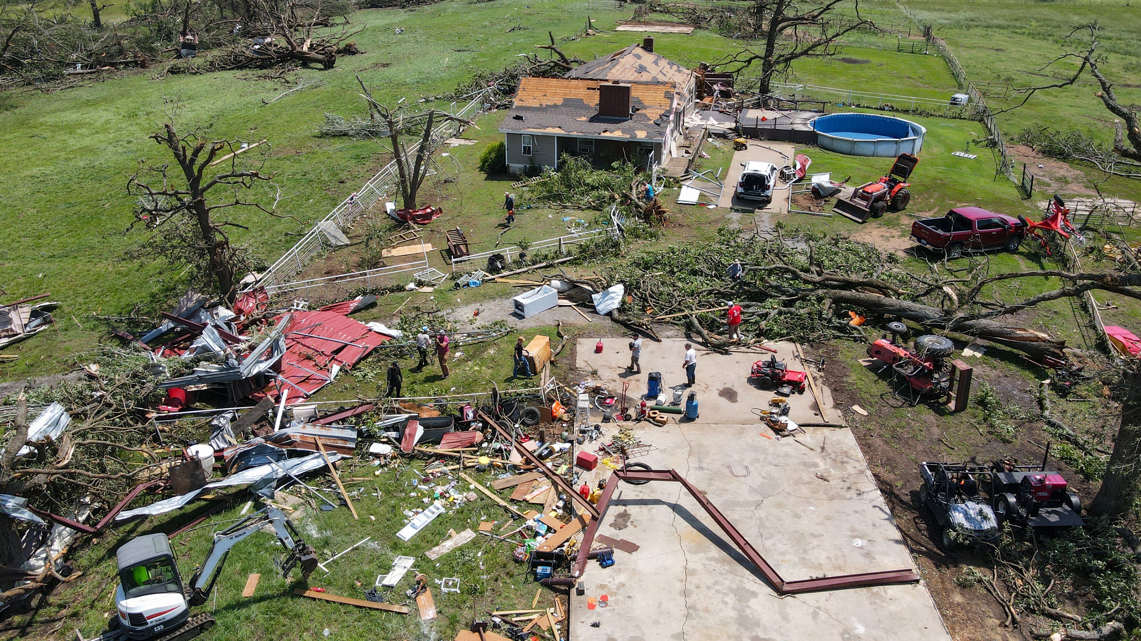 People clean up storm damage at the Baldridge family home Sunday, May 26, 2024 in Pryor, Ok. Two women were killed during the storm at a home next door.
