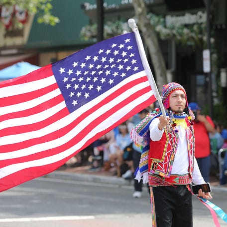 A member of the Peruvian Community of Freehold waves an American flag along West Main Street in Freehold Borough during the 150th Annual Memorial Day Parade there Monday, May 27, 2024.