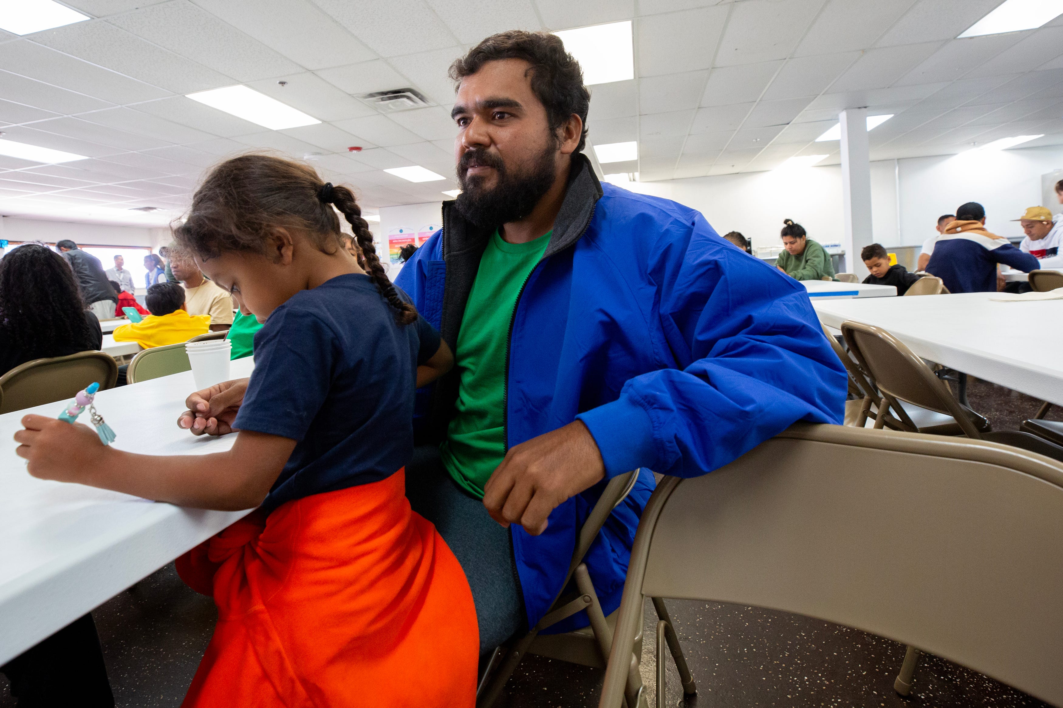 Elisaul Mora and his 5-year-old daughter eat lunch in the cafeteria of a migrant shelter in El Paso, Texas. Mora described a dangerous experience after having crossed into the U.S. from Ciudad Juarez on May 7, 2024.