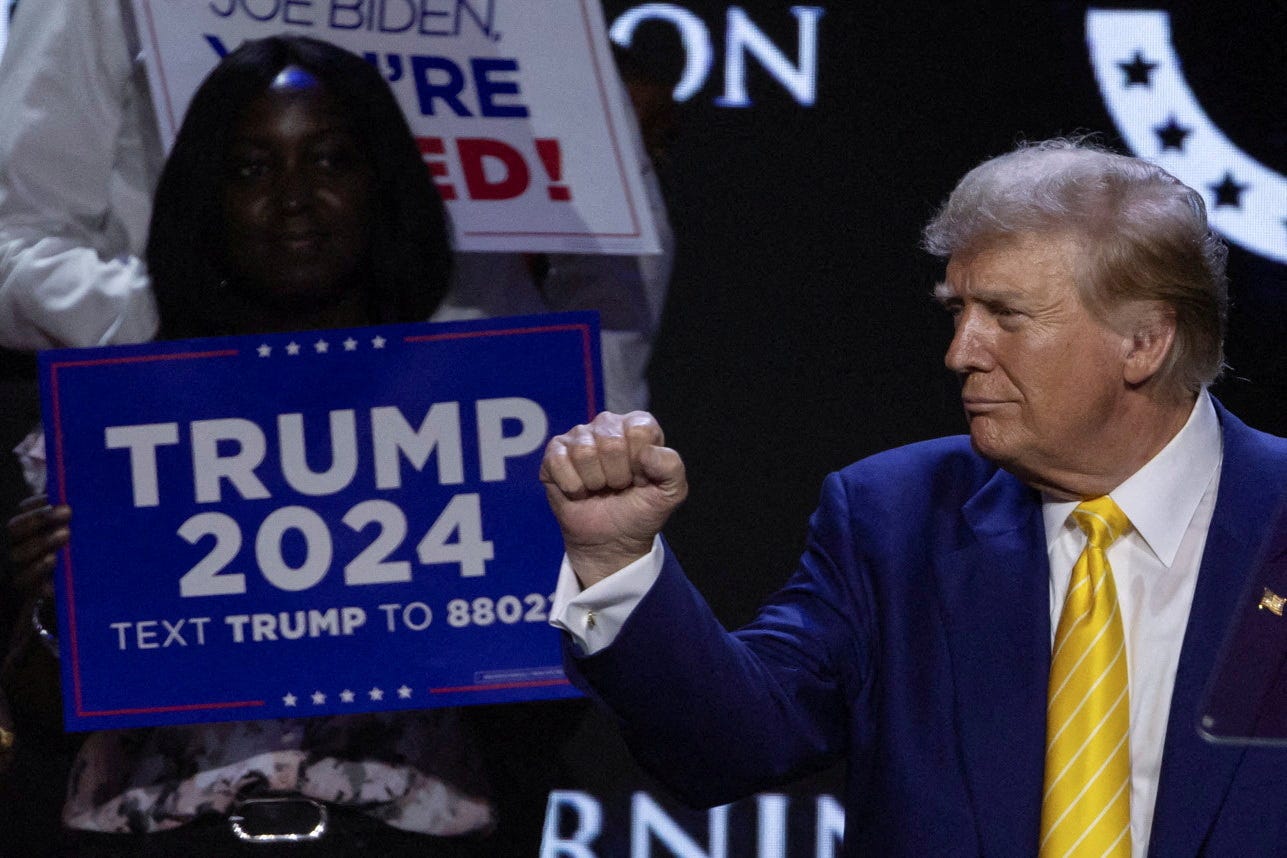 Republican presidential candidate and former U.S. President Donald Trump gestures as a supporter looks on during a Turning Point USA event at the Dream City Church in Phoenix, Arizona on June 6, 2024.