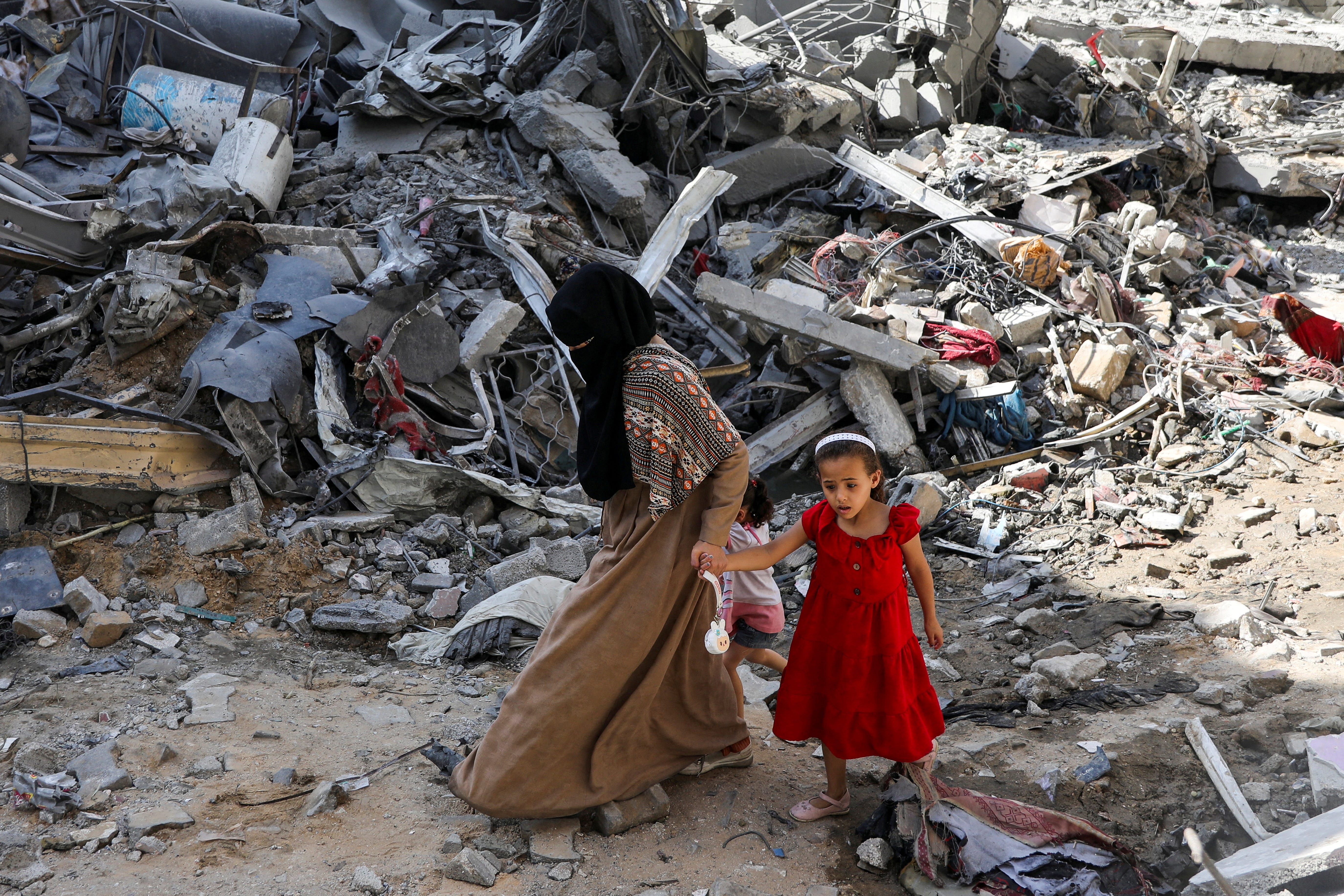 A woman and child walk among debris after an Israeli raid that freed four hostages in Nuseirat refugee camp in the central Gaza Strip, June 9, 2024.