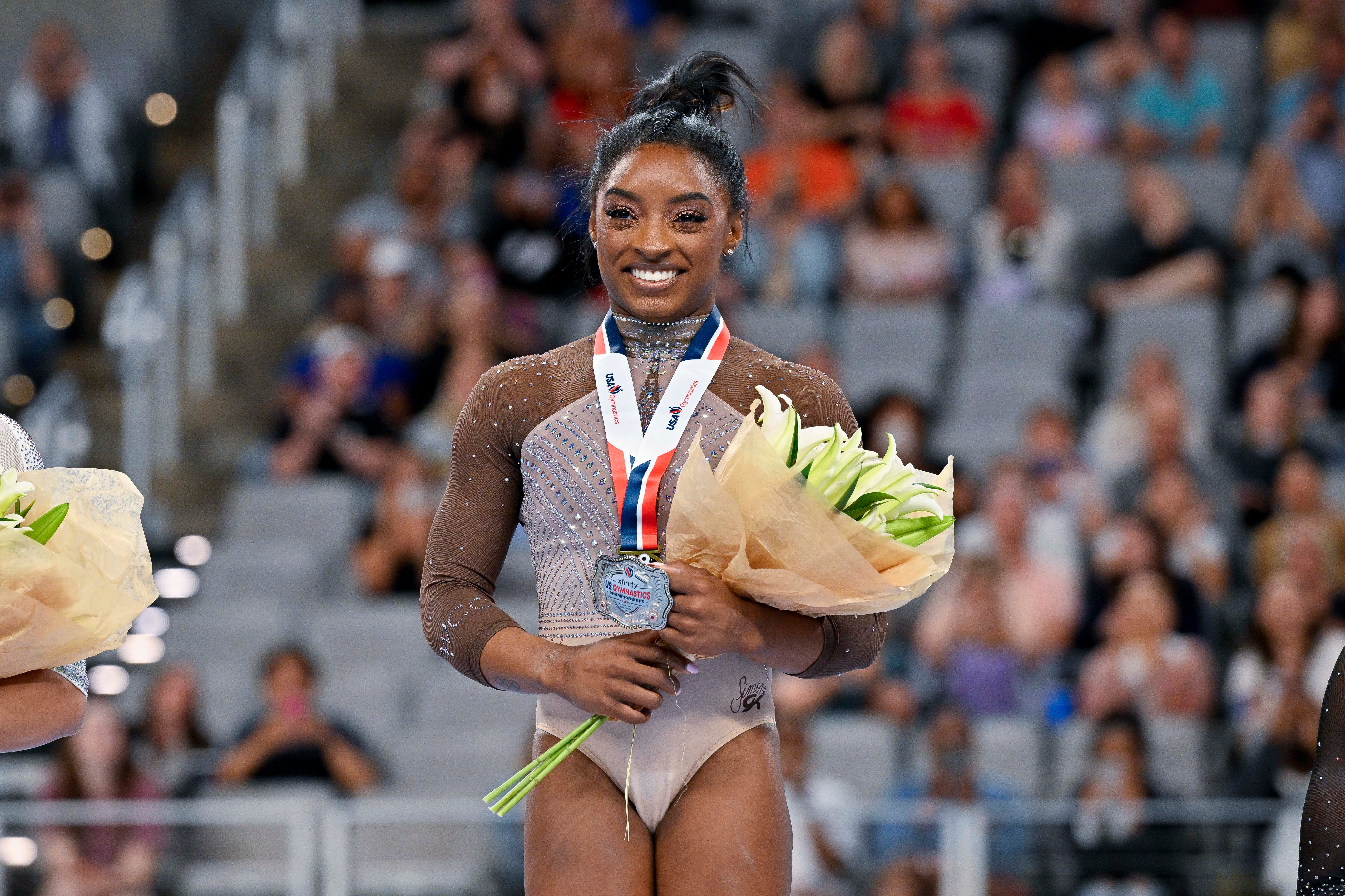 Jun 2, 2024; Fort Worth, Texas, USA; Simone Biles of World Champions Centre poses for a photo with her gold medal and commemorative belt buckle after finishing in first in the women's 2024 Xfinity U.S. Gymnastics Championships at Dickies Arena.