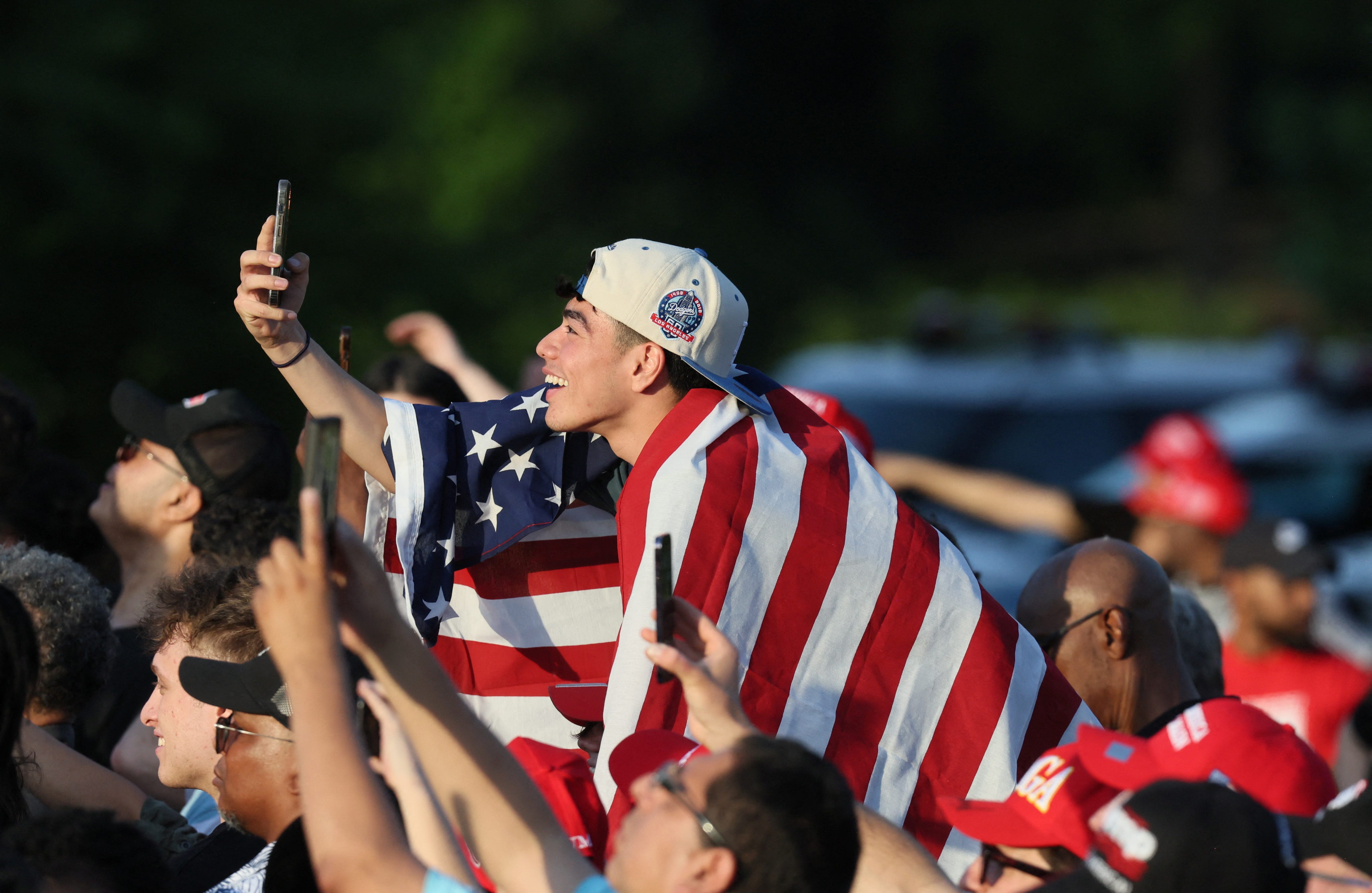 A young man draped in the U.S. flag attends a campaign rally attended by former U.S. President Donald Trump at Crotona Park in Bronx, New York on May 23, 2024.