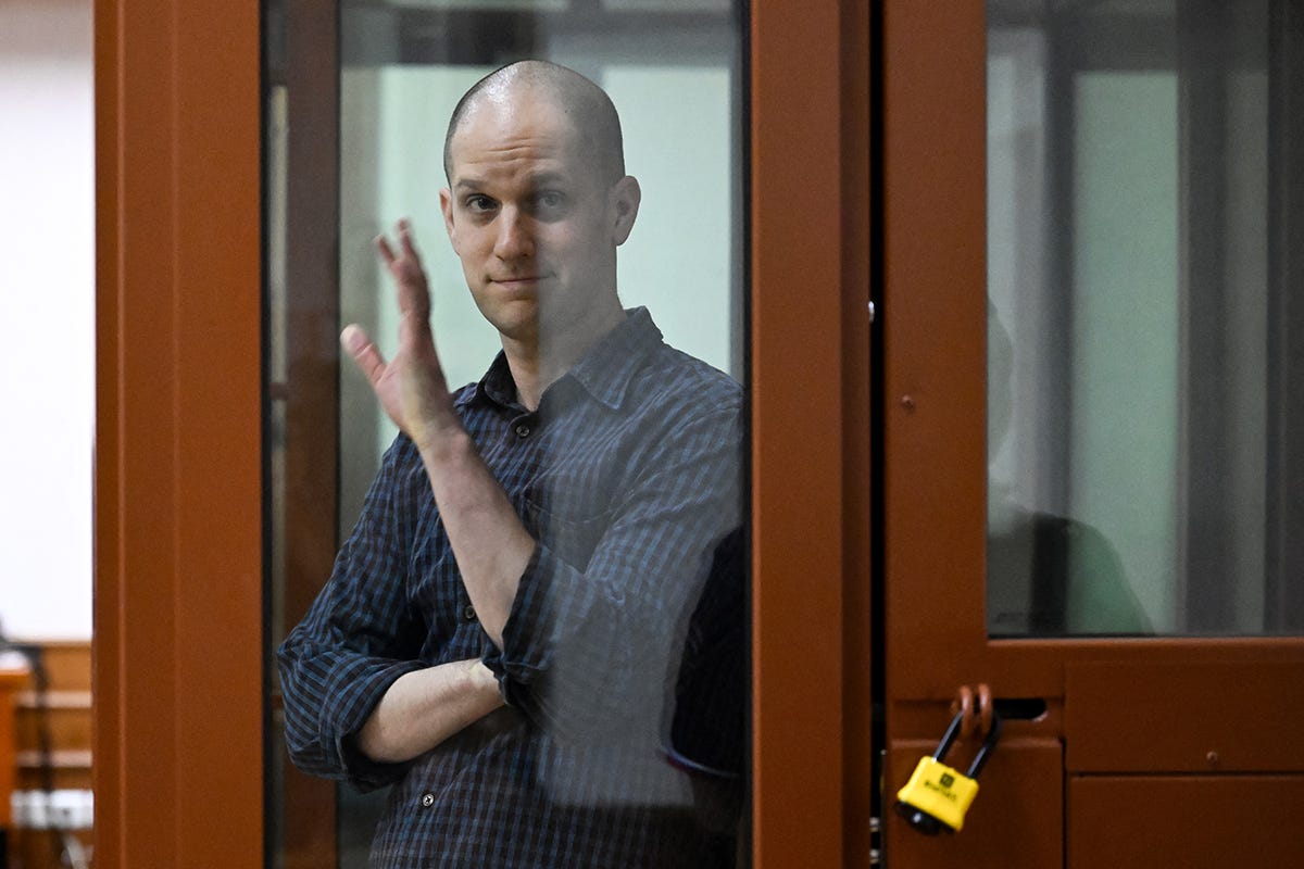Wall Street Journal journalist Evan Gershkovich, accused of espionage, gestures from inside a glass defendants' cage on June 26, 2024, at regional court in Russia. On July 19, he was sentenced to 16 years in prison.