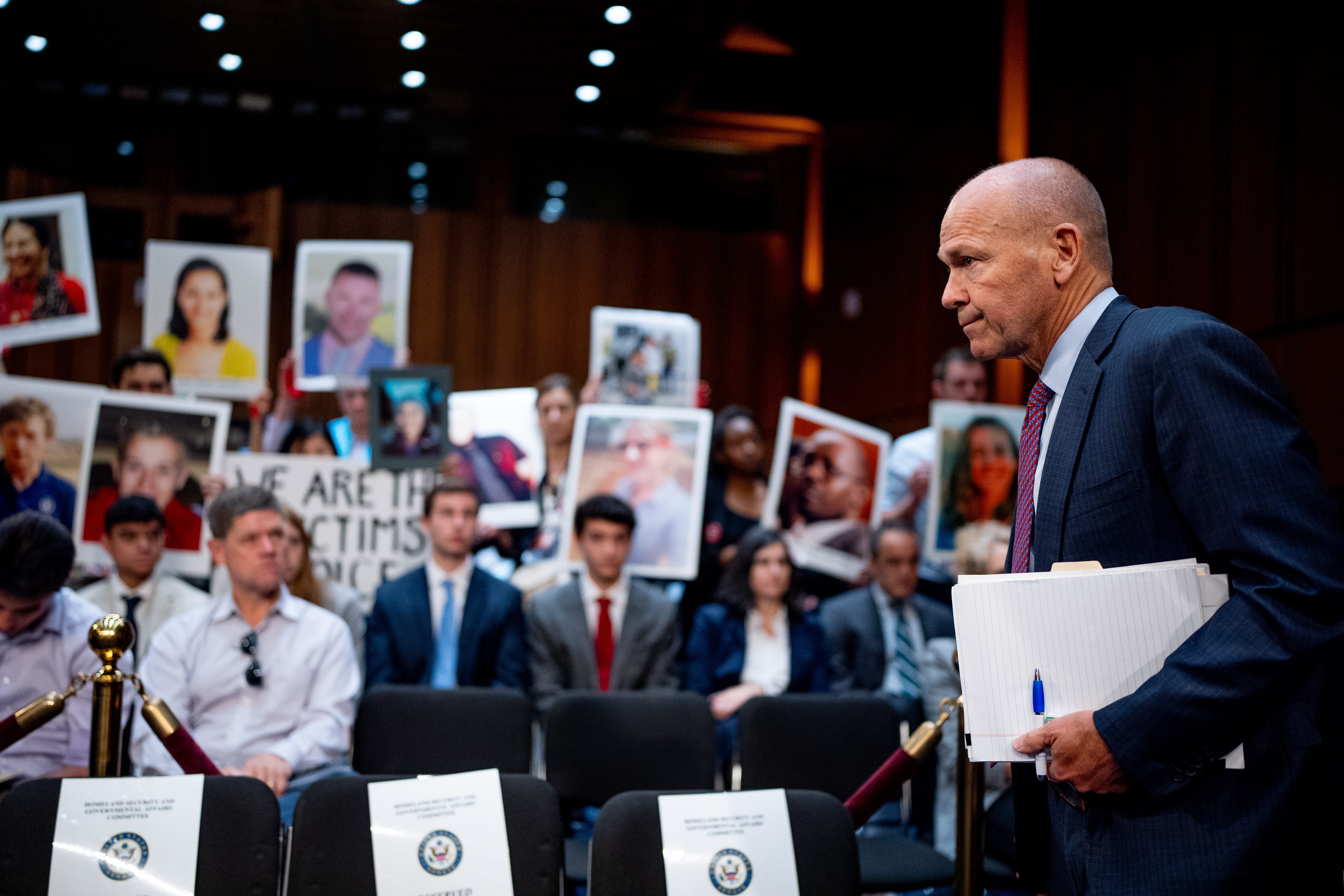 Boeing CEO Dave Calhoun arrives as family members of those killed in the Ethiopian Airlines Flight 302 and Lion Air Flight 610 crashes hold up photographs of their loved ones before a Senate Homeland Security and Governmental Affairs Investigations Subcommittee hearing on Boeing's broken safety culture on Capitol Hill in Washington, D.C., on June 18, 2024.