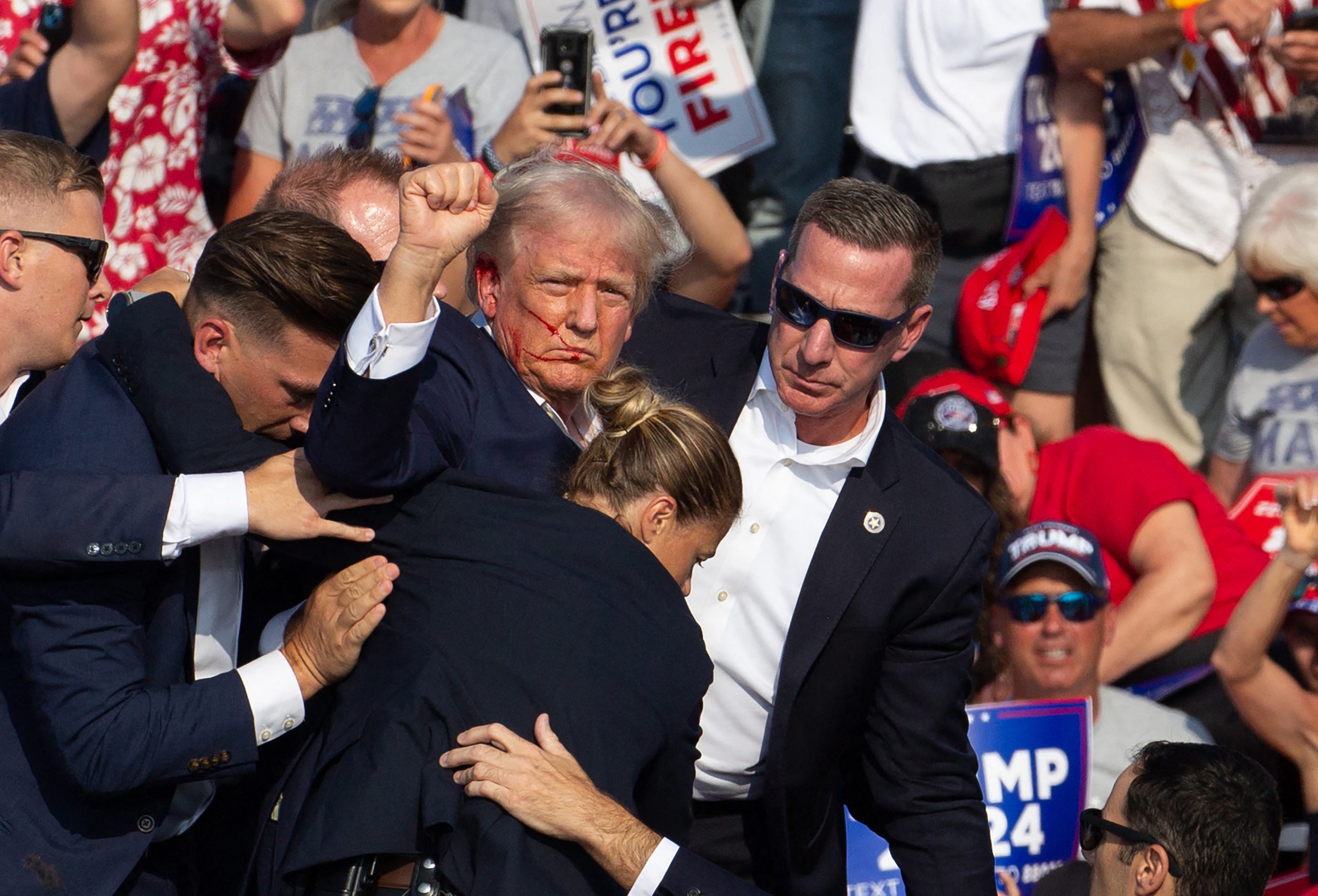 Republican candidate Donald Trump is seen with blood on his face surrounded by secret service agents as he is taken off the stage at a campaign event at Butler Farm Show Inc. in Butler, Pennsylvania, July 13, 2024. Donald Trump was hit in the ear in an apparent assassination attempt by a gunman at a campaign rally on Saturday, in a chaotic and shocking incident that will fuel fears of instability ahead of the 2024 US presidential election. The 78-year-old   former president was rushed off stage with blood smeared across his face after the shooting in Butler, Pennsylvania, while the gunman and a bystander were killed and two spectators critically injured.