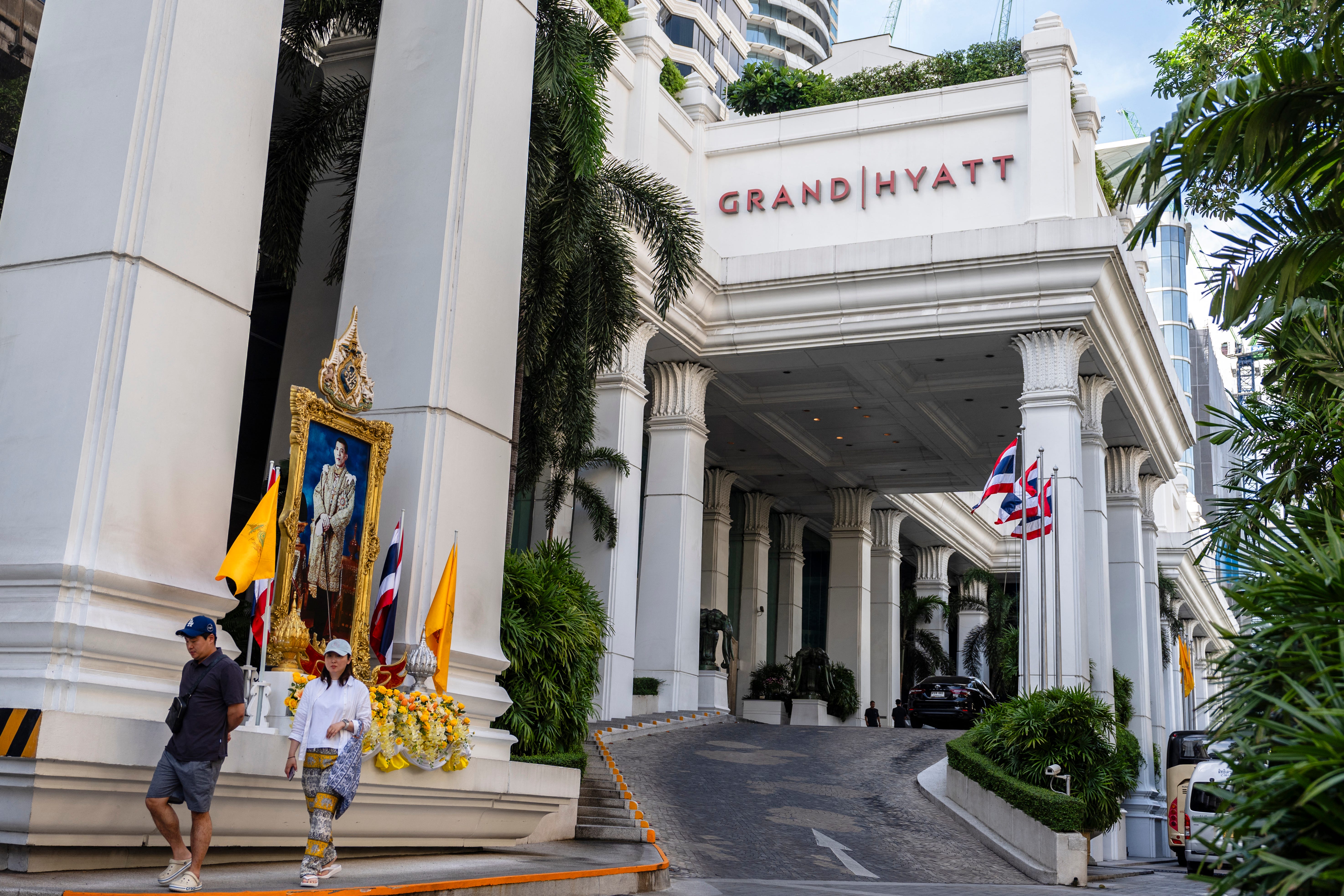 People walk past the main entrance of the Grand Hyatt Erawan hotel in Bangkok on July 17, 2024, the day after six bodies were found dead inside the hotel allegedly due to poisoning.