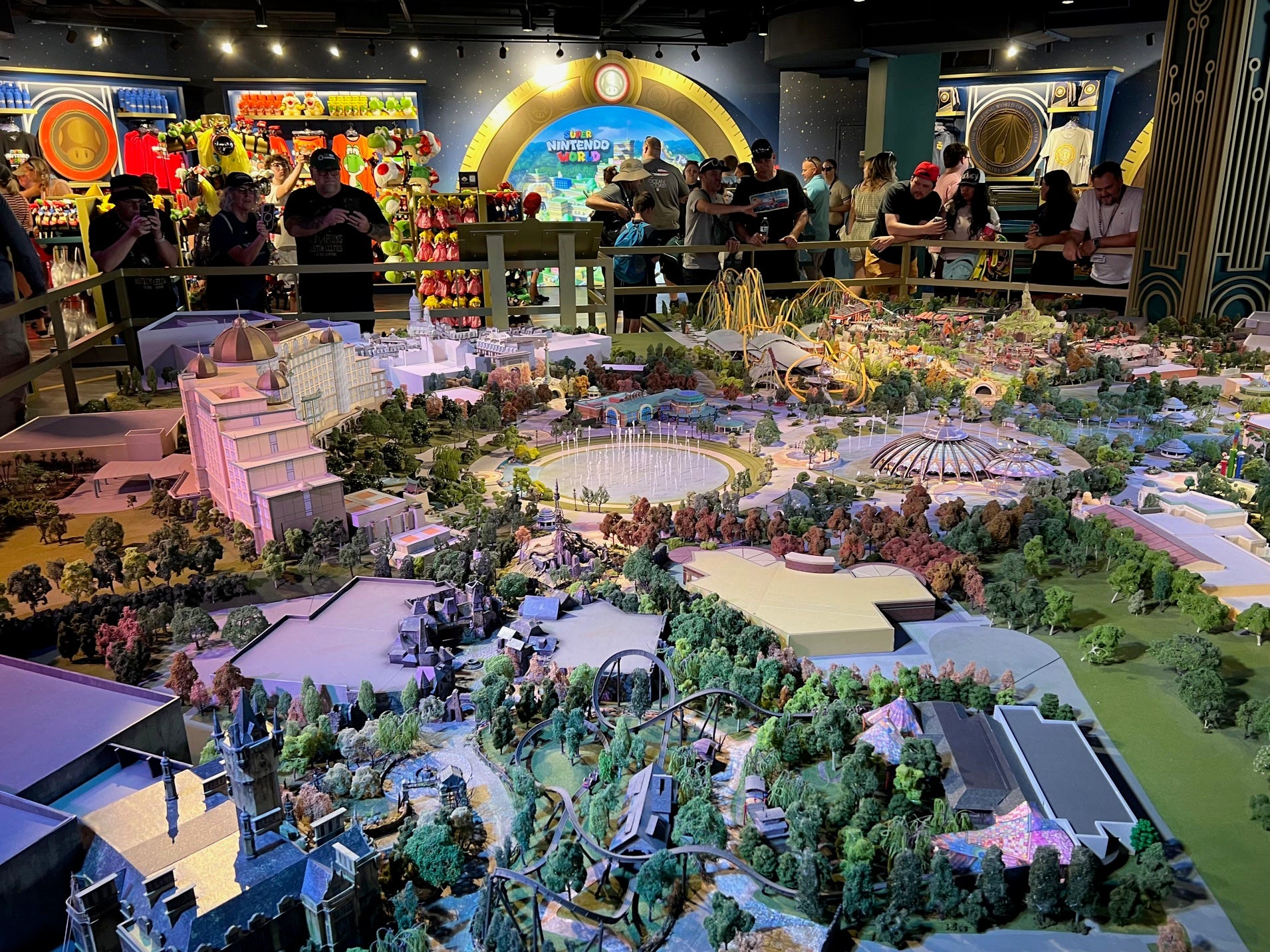 People gather around a sprawling model of the new park at Universal Orlando's Epic Universe Preview Center.