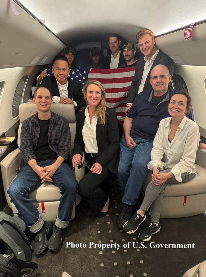 Evan Gershkovich, Paul Whelan and Alsu Kurmasheva, who were detained in Russia, pose with others aboard an aircraft after they were released, in this undated handout photograph obtained on August 1, 2024.