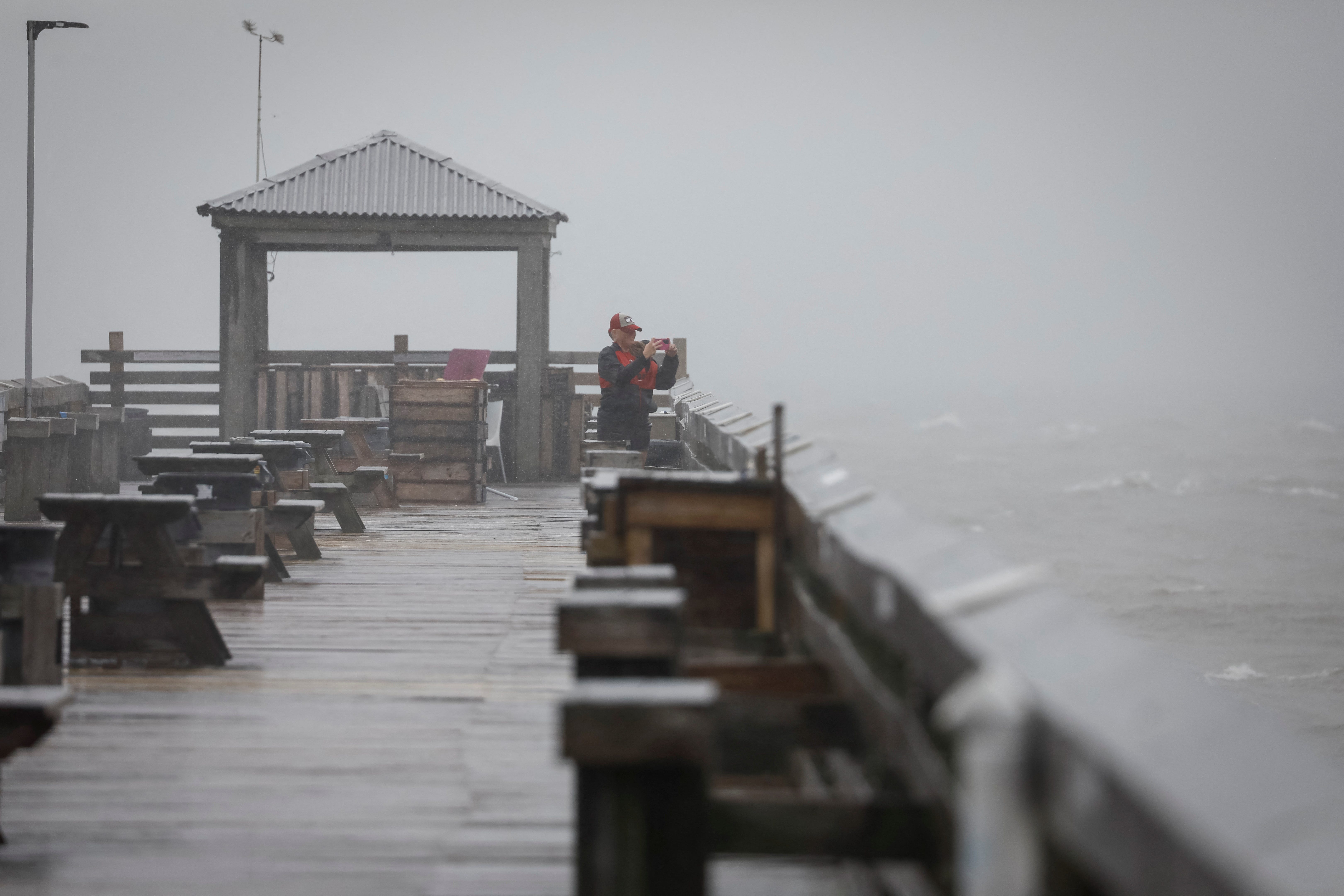 A woman uses her phone to capture images from the pier as Tropical Storm Debby drifts in the East Coast, in Myrtle Beach, South Carolina on August 7, 2024.