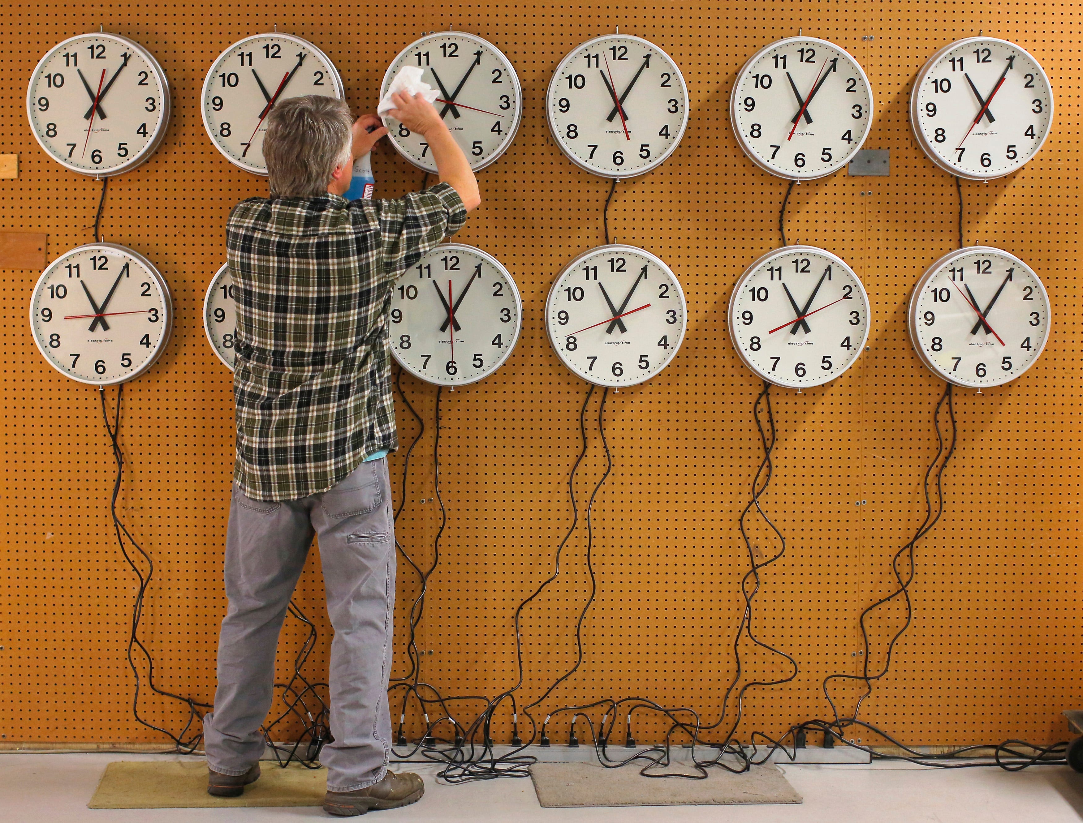 Scott Gow cleans the faces of wall clocks being tested before going to a Capital Grill restaurant at the Electric Time Company in Medfield, Massachusetts November 1, 2013. Daylight saving time in the United States ends at 2:00 a.m. local time on November 3.