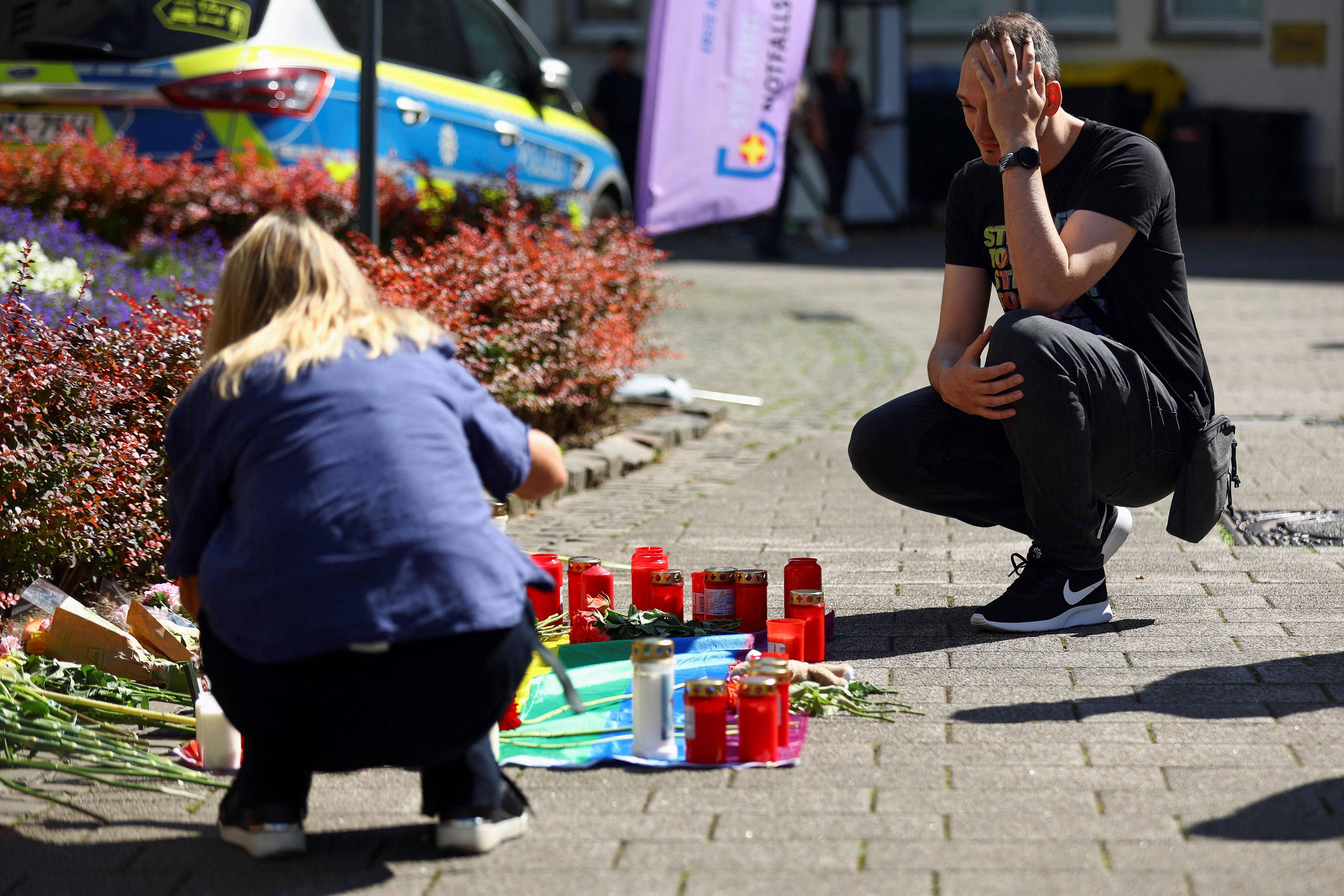 A man reacts next to candles and floral tributes in Solingen, Germany, Aug. 24, 2024, after a stabbing attack that killed several people. A man randomly stabbed passersby with a knife at a city festival the day before.