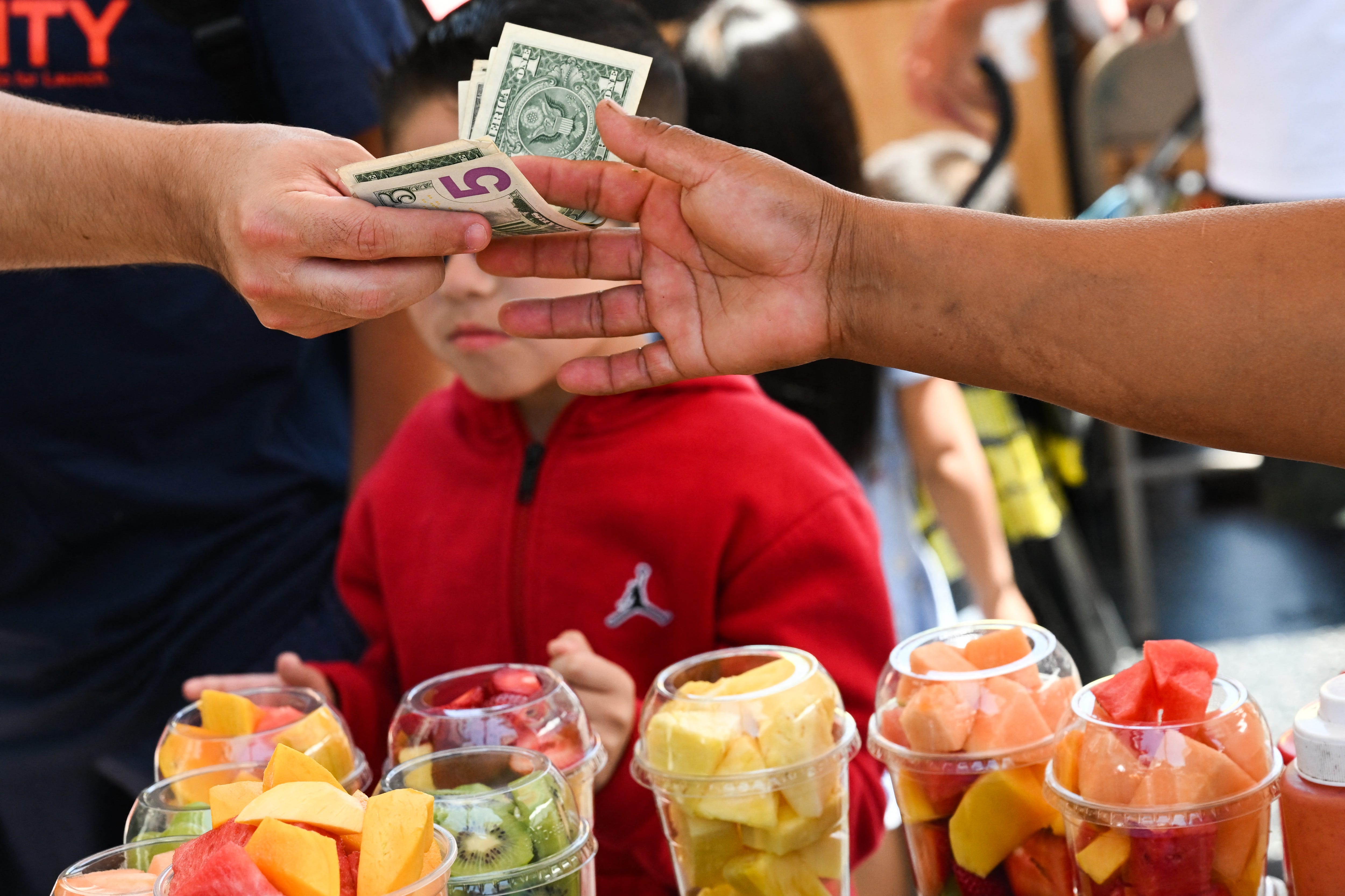 A customer pays cash for a container of fresh fruit from a street vendor along Hollywood Blvd on July 13, 2022, in Los Angeles, California. US consumer price inflation surged 9.1 percent over the past 12 months to June, the fastest increase since November 1981, according to government data released on July 13. The Labor Department reported that the consumer price index jumped 1.3 percent in June driven by record-high gasoline prices.