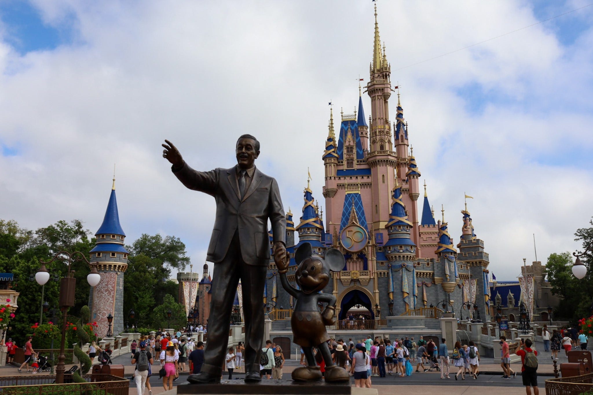 Celebrating the park's 50th Anniversary, visitors to Disney's Magic Kingdom pass a statue of Walt Disney holding hands with Mickey Mouse.    Disney World Magic Kingdom Walt Disney Statue