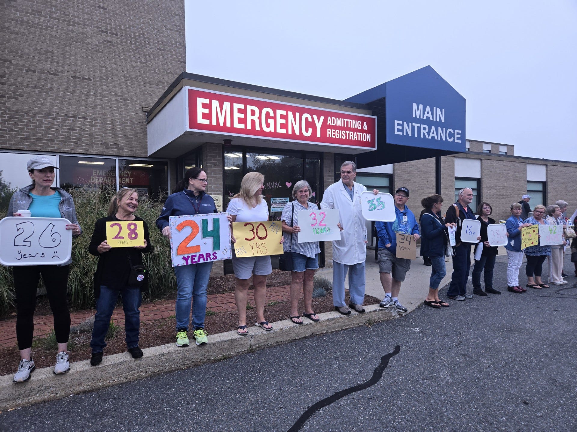 Members of Nashoba Valley Medical Center's staff stand outside the hospital after it was officially closed to patients on Saturday. Staff held up signs acknowledging their decades of service at the hospital.
