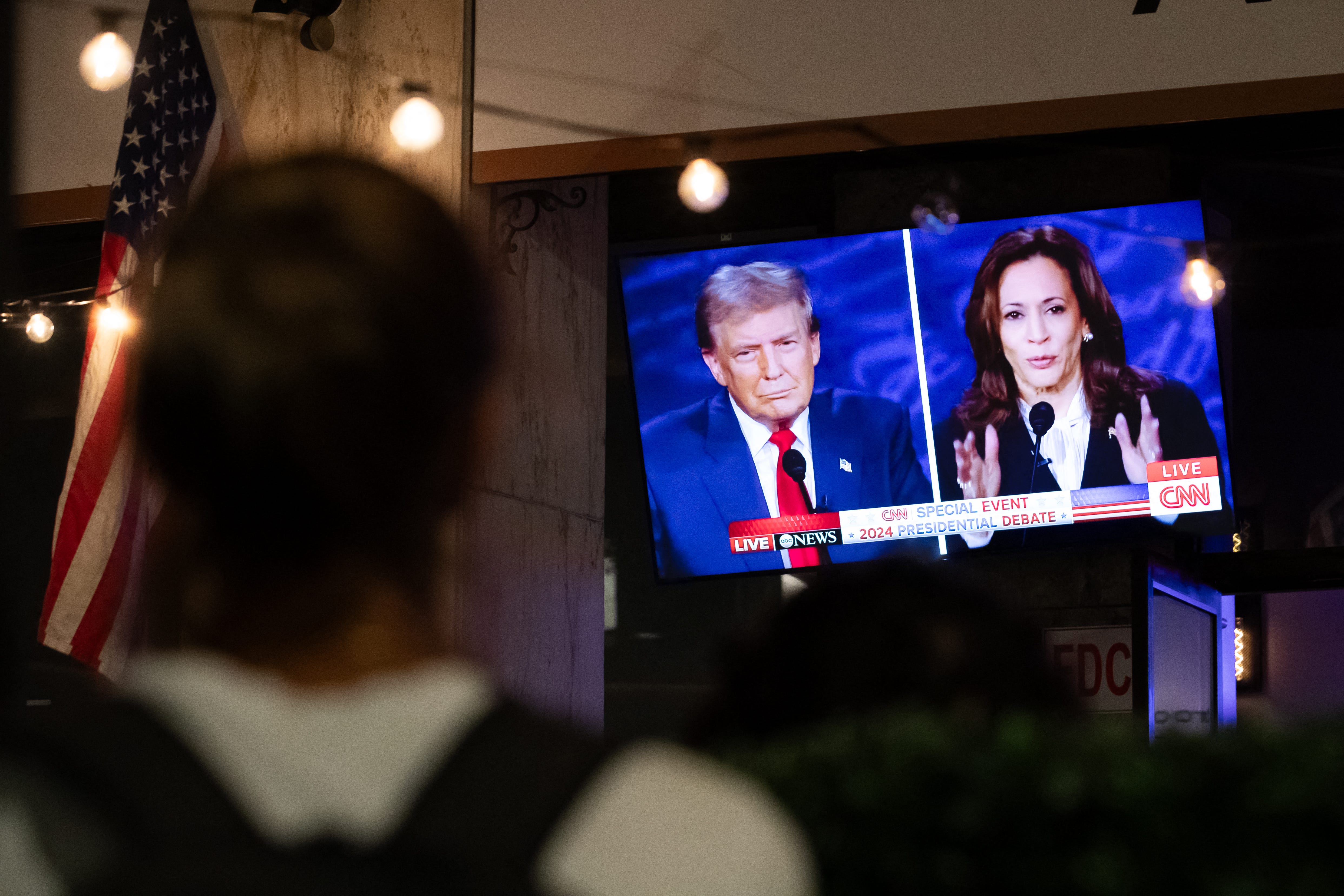 A walking past stops to watch a screen displaying the US Presidential debate between Vice President and Democratic presidential candidate Kamala Harris and former US President and Republican presidential candidate Donald Trump at The Admiral in Washington, DC, on September 10, 2024. (Photo by Allison Bailey / AFP) (Photo by ALLISON BAILEY/AFP via Getty Images)