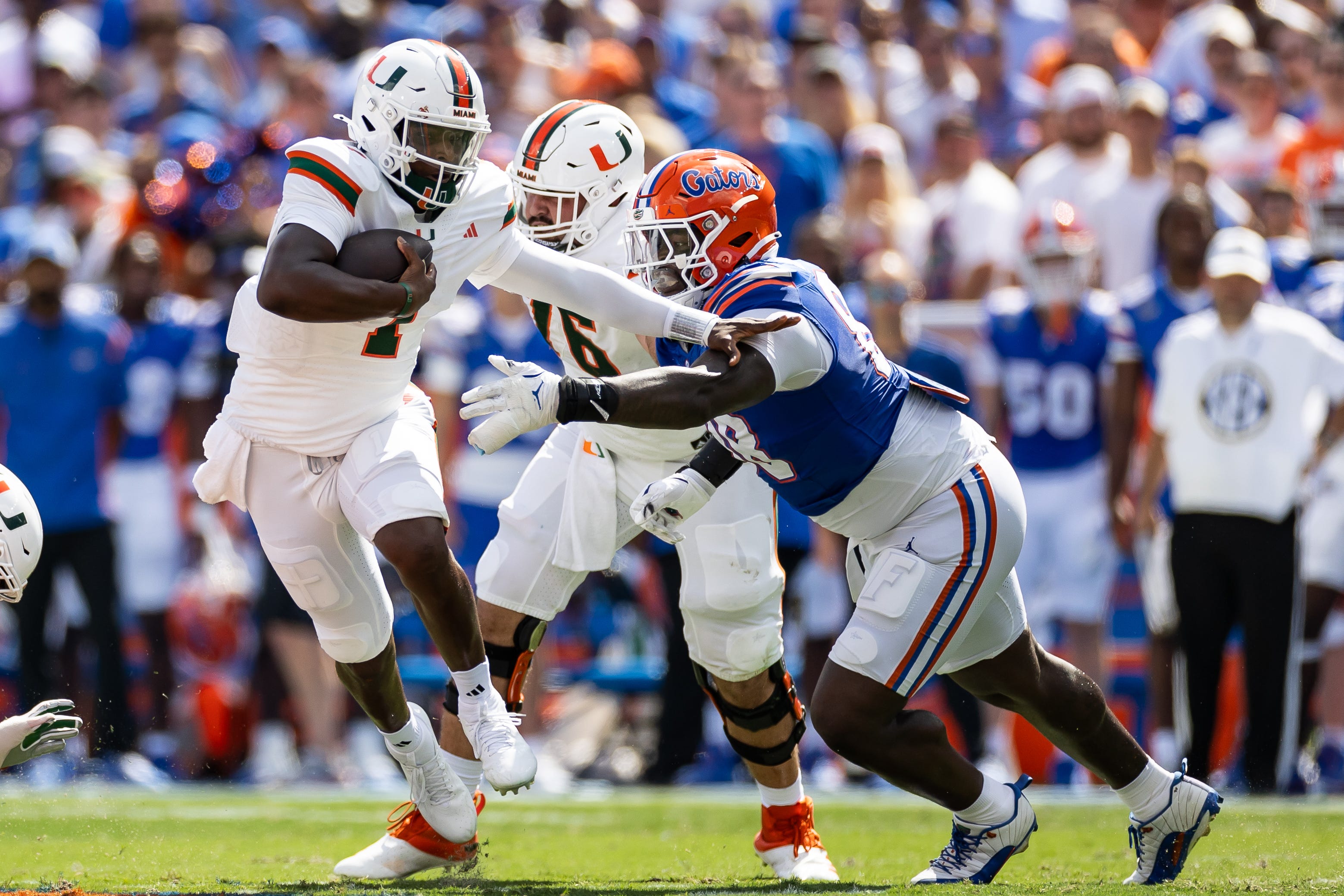 Miami quarterback Cam Ward (1) runs past Florida defensive lineman Caleb Banks (88) during their game at Ben Hill Griffin Stadium.