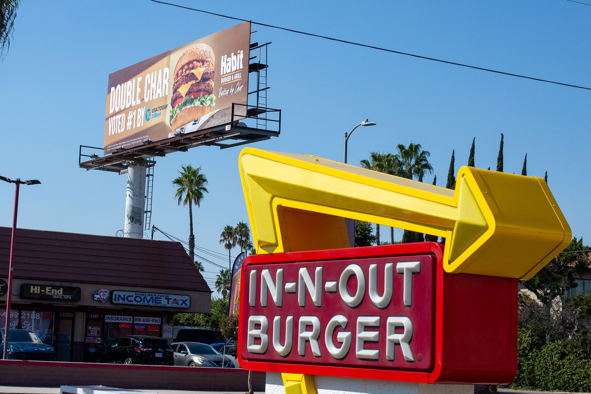 A billboard touting The Habit's ranking number one in a USA TODAY 10 BEST list is seen next to an In-N-Out location in the Van Nuys neighborhood in Los Angeles, Calif. on Tuesday, October 1, 2024.