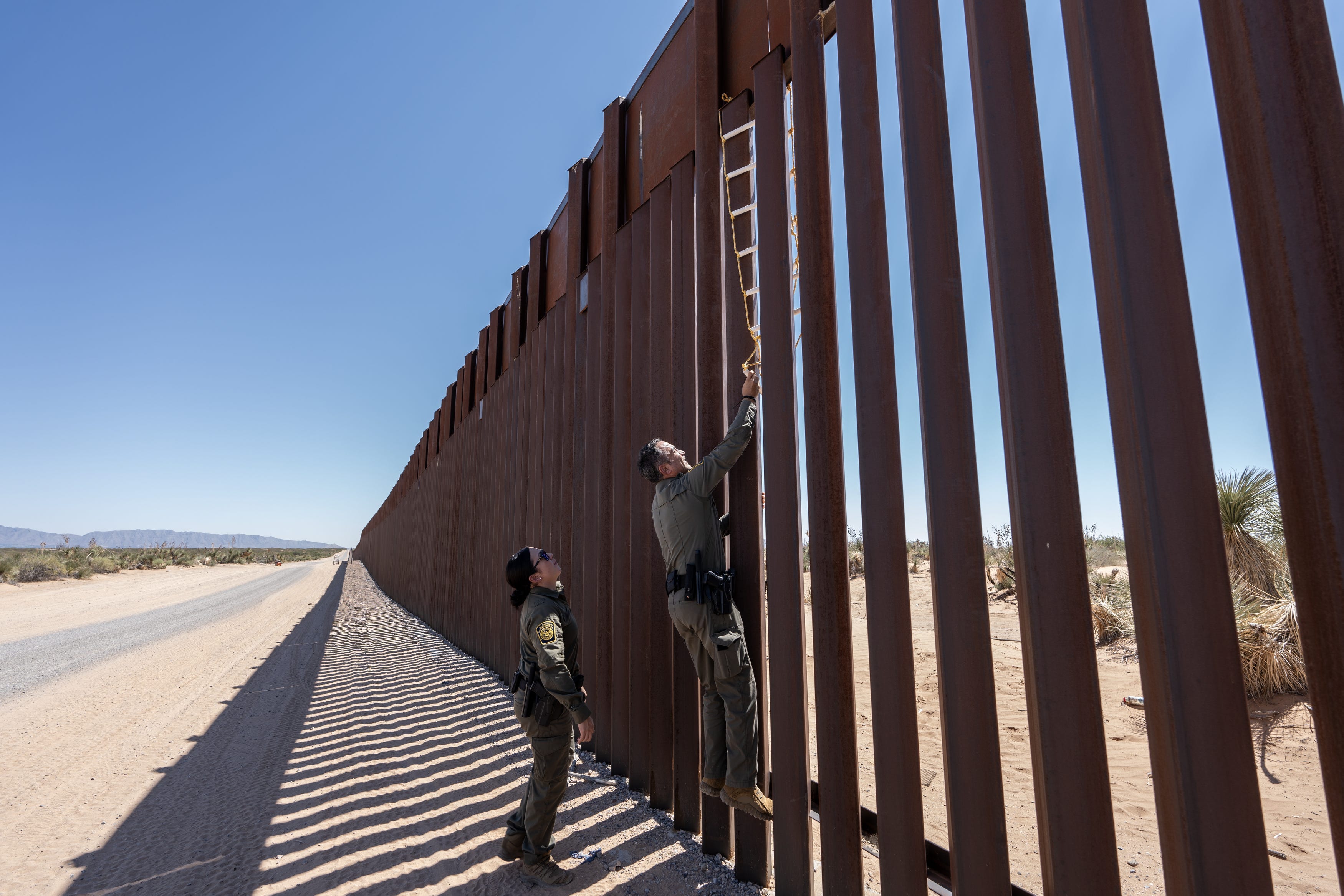 Border Patrol Agent Claudio Herrera tries to dislodge a homemade latter used by migrants to climb the border wall in the desert in Santa Teresa, New Mexico.