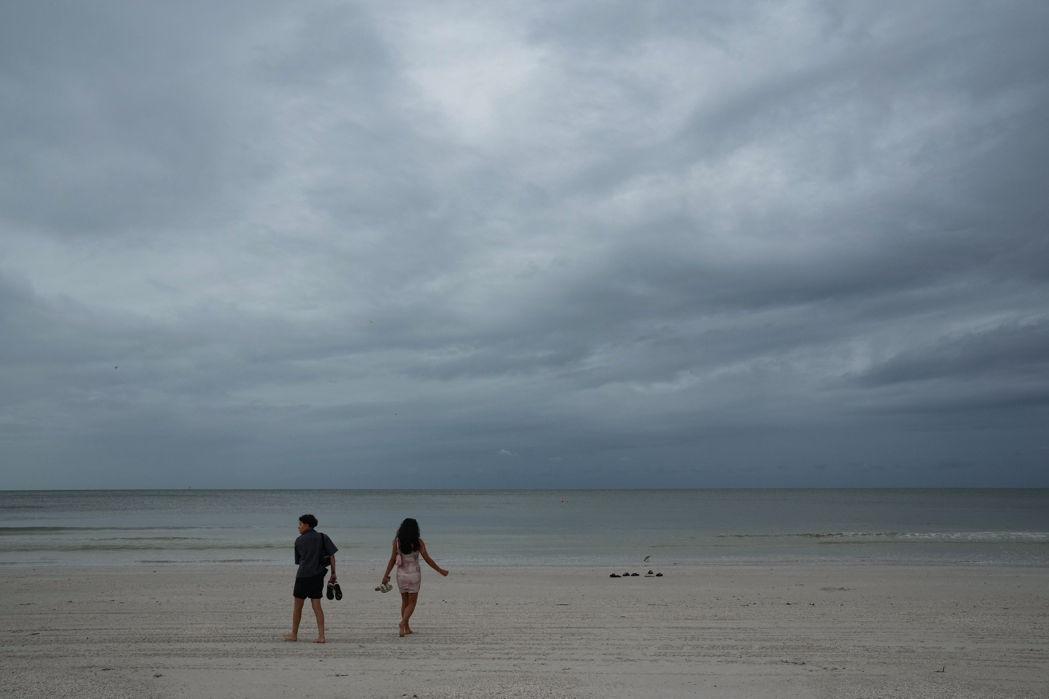 A couple walks along the beach in Clearwater, Florida on October 6, 2024, ahead of Hurricane Milton's expected mid-week landfall.
