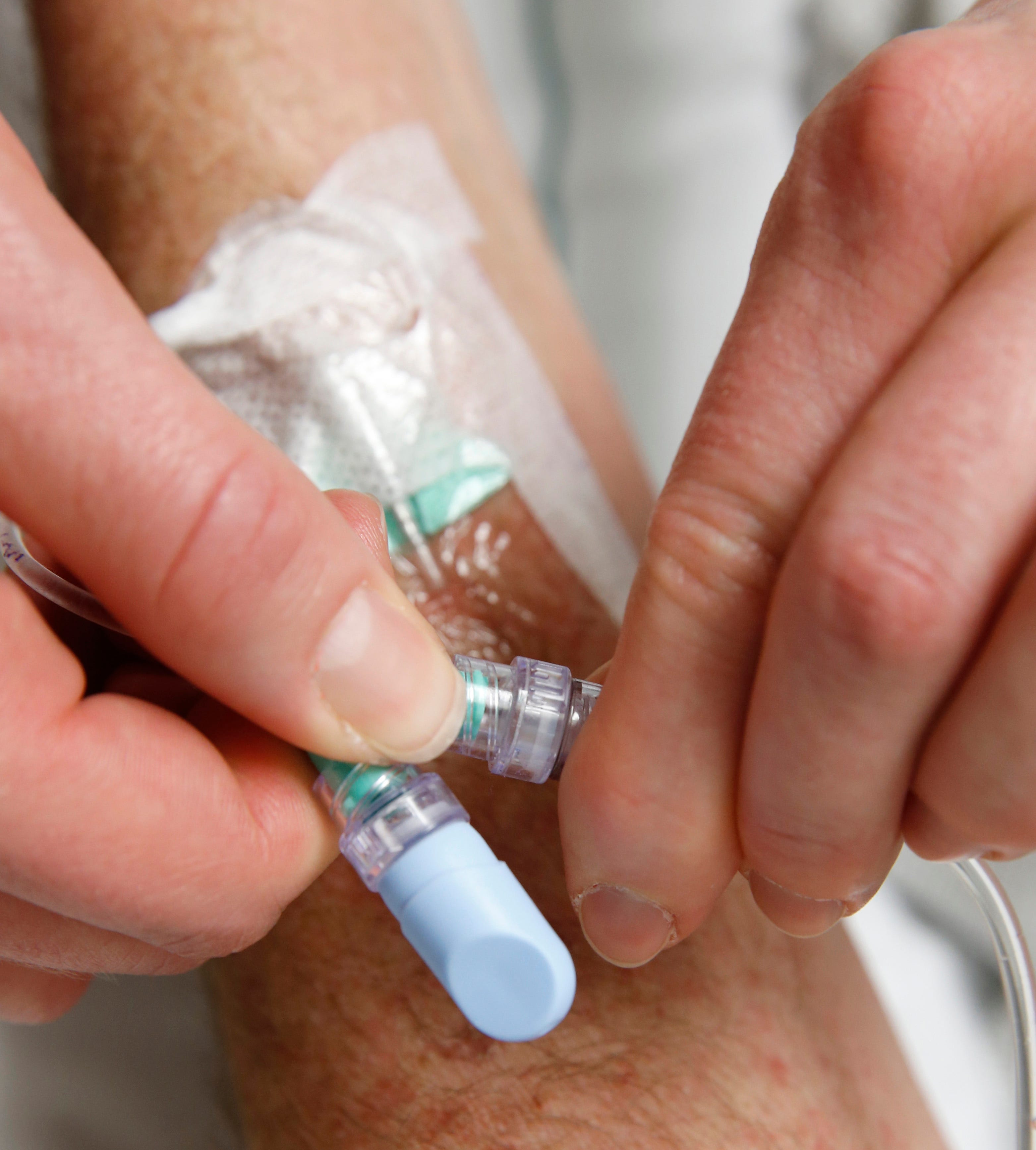 A nurse attaches a bag of saline to a patient's IV catheter. Hospitals are urging the Biden administration to take immediate steps to avert shortages of a common saline used in hospitals and dialysis centers after flooding from Hurricane Helene temporarily closed a North Carolina factory. REUTERS/George Frey (UNITED STATES - Tags: HEALTH)