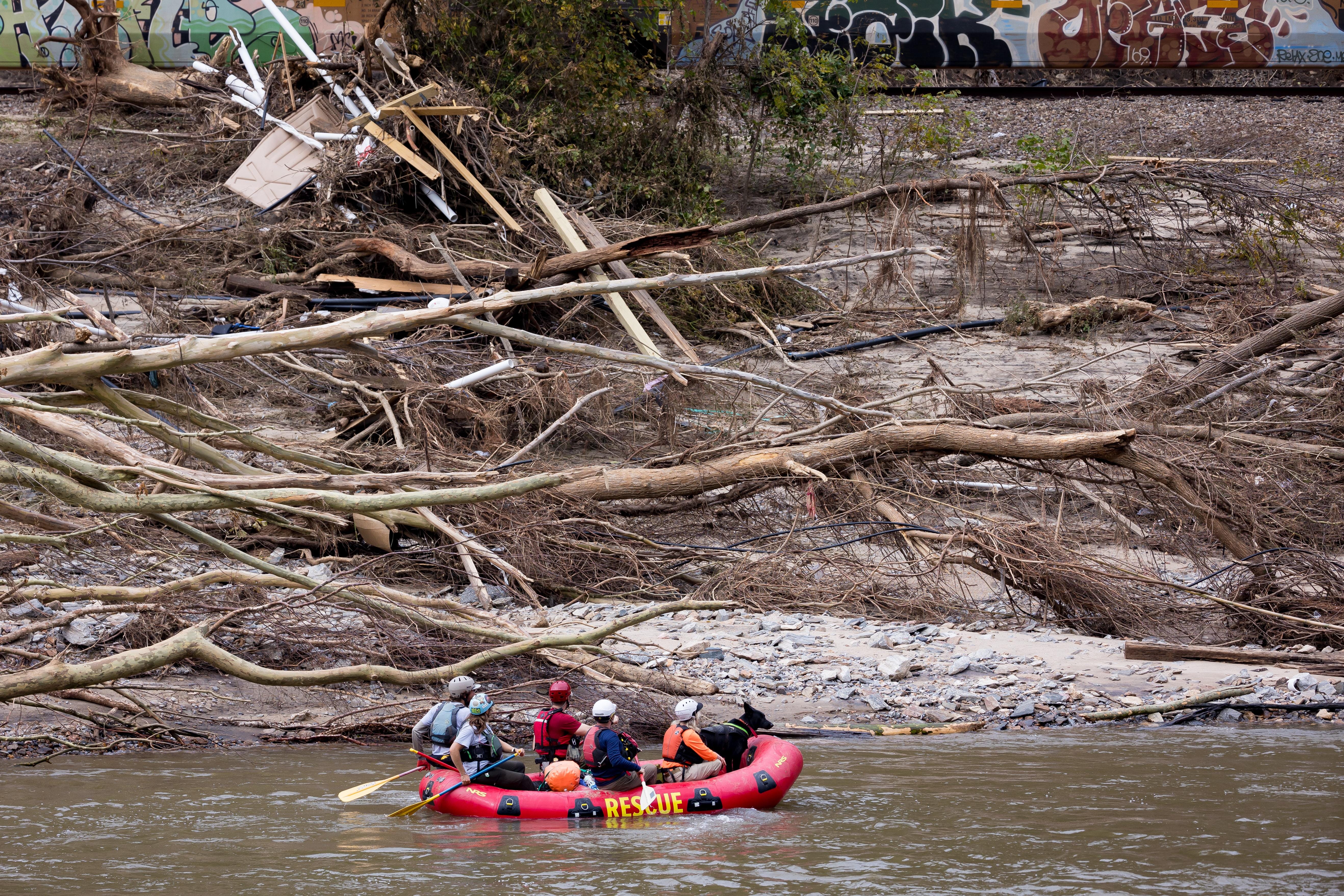 Oct 4, 2024; Asheville, NC, USA: Lisa Briggs, director of emergency and disaster management at Western Carolina University, director of the university's cadaver dog training program, Walnut fire department volunteers and Omna, a 5-year-old full German Shepherd, a cadaver dog, paddle close to the edge at French Broad River during a search and rescue operation on Friday, Oct. 4, 2024, during the aftermath of flooding caused by the remnants of Hurricane   Helene. Mandatory Credit: Gaby Velasquez-USA TODAY