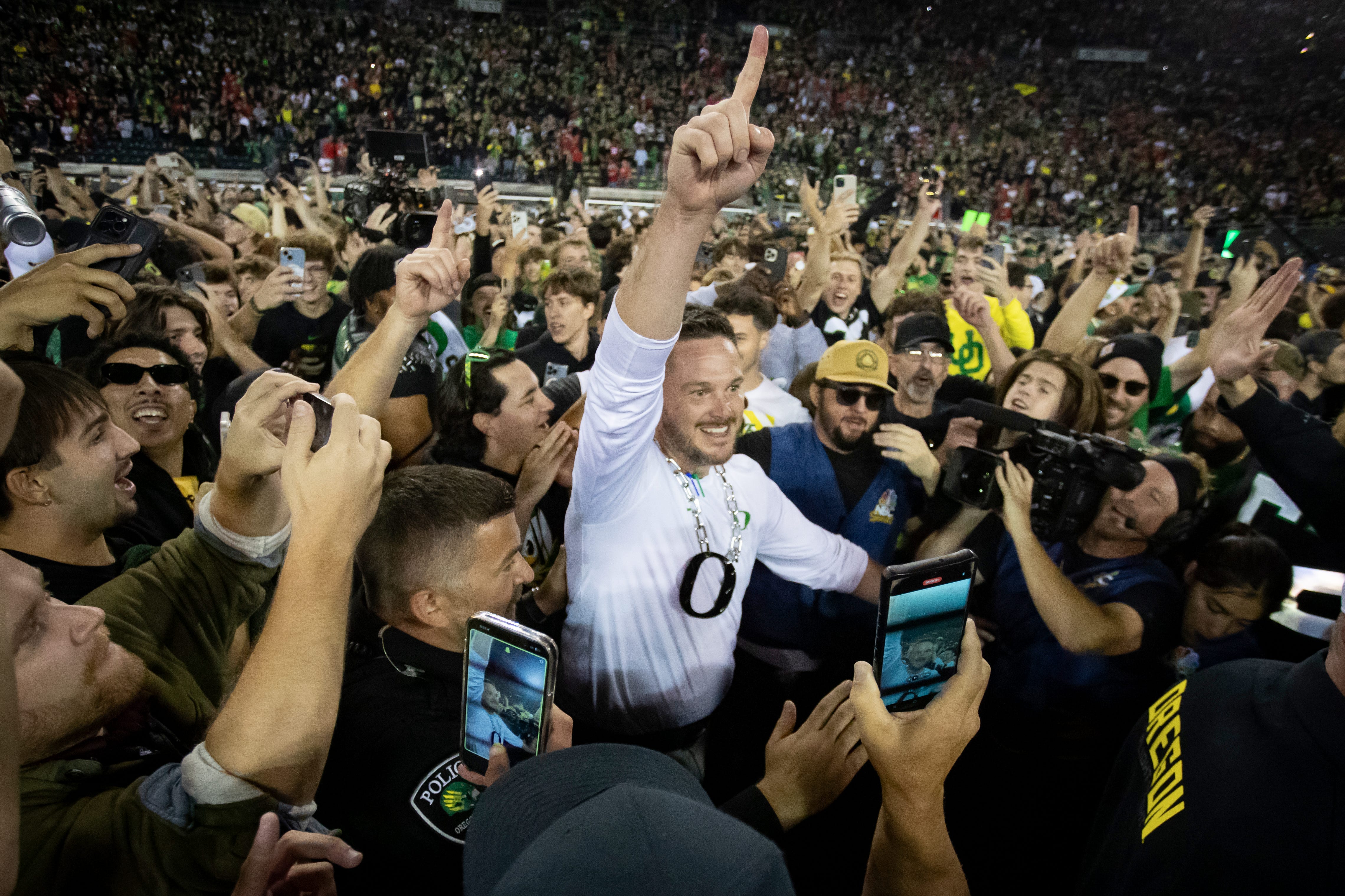 Oregon Ducks head coach Dan Lanning celebrates amid a crowd of fans on the field as the No. 3 Oregon Ducks knock off the No. 2 Ohio State Buckeyes 32-31 Saturday, Oct. 12, 2024 at Autzen Stadium in Eugene, Ore.