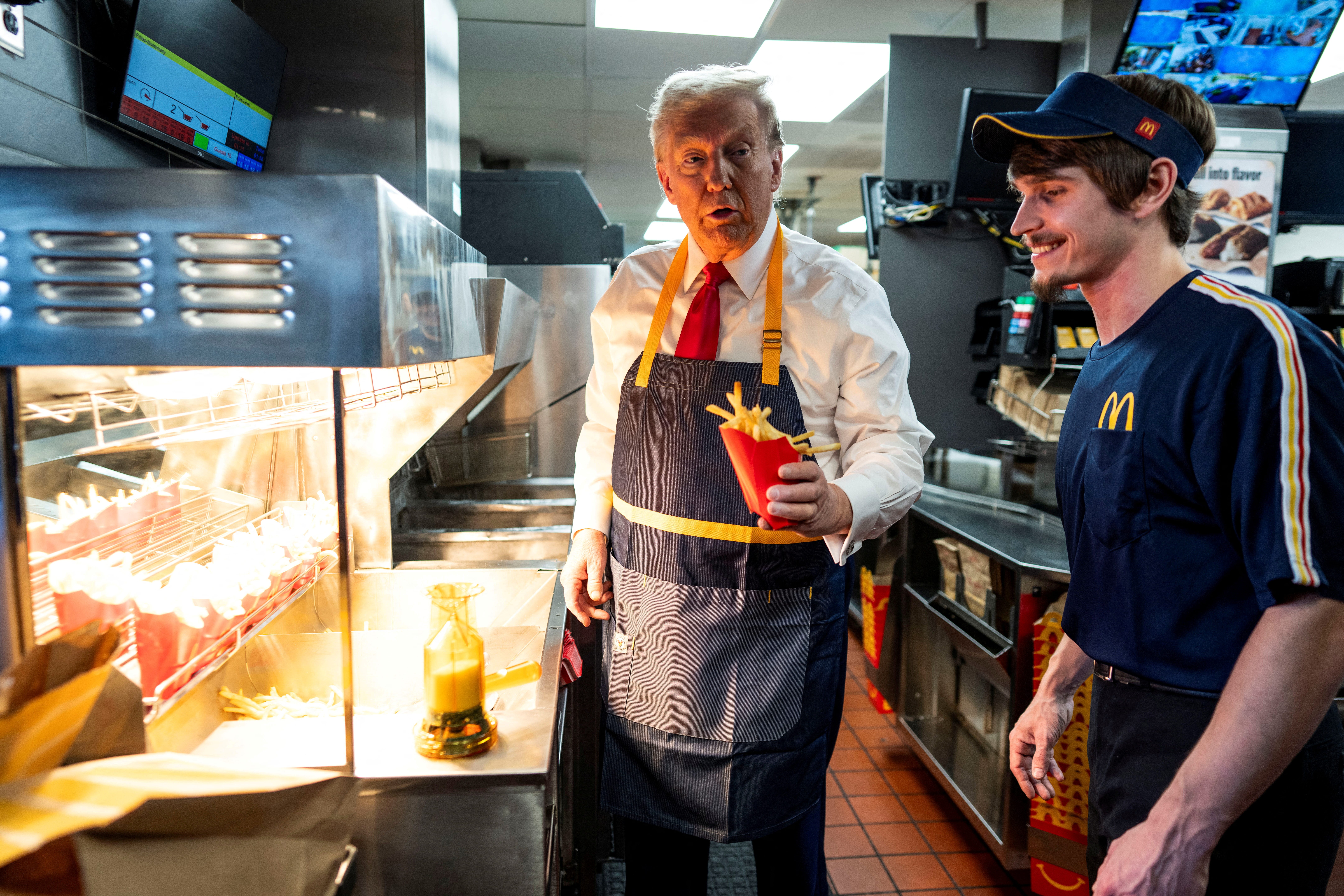 Republican presidential nominee and former U.S. President Donald Trump works behind the counter during a visit to McDonald's in Feasterville-Trevose, Pennsylvania, U.S. October 20, 2024.