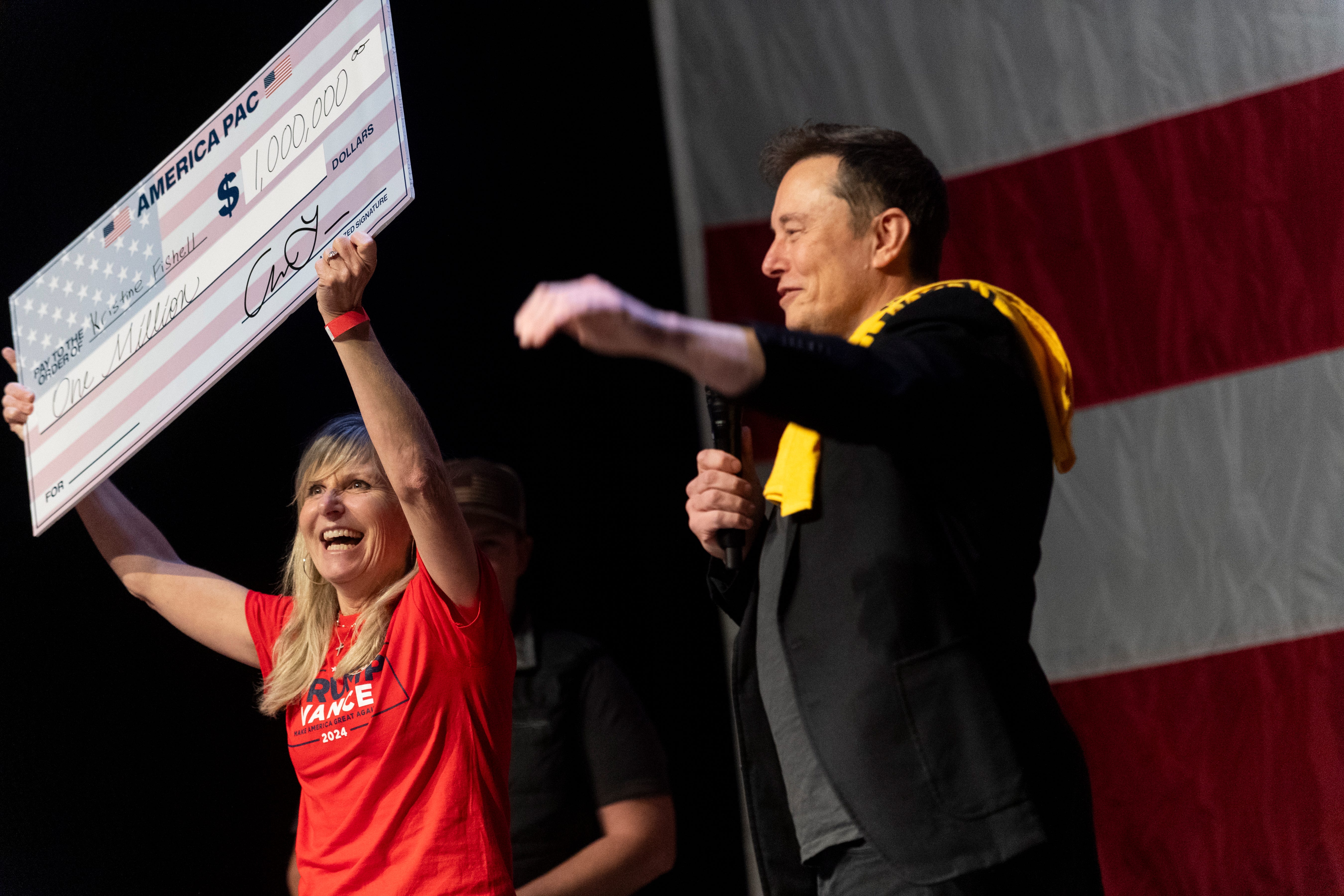 SpaceX and Tesla founder Elon Musk awards a swing state voter with a $1 million check during a town hall on Oct. 20, 2024, in Pittsburgh. Former Republican lawmakers, Justice Department officials and advisers have asked Attorney General Merrick Garland to investigate the billionaire for handing out $1 million prizes to registered voters if they sign his political organization's petition. Their letter argues that the prizes, established by Musk as part of his effort   to help elect former President Donald Trump, violate laws against paying people to register to vote.