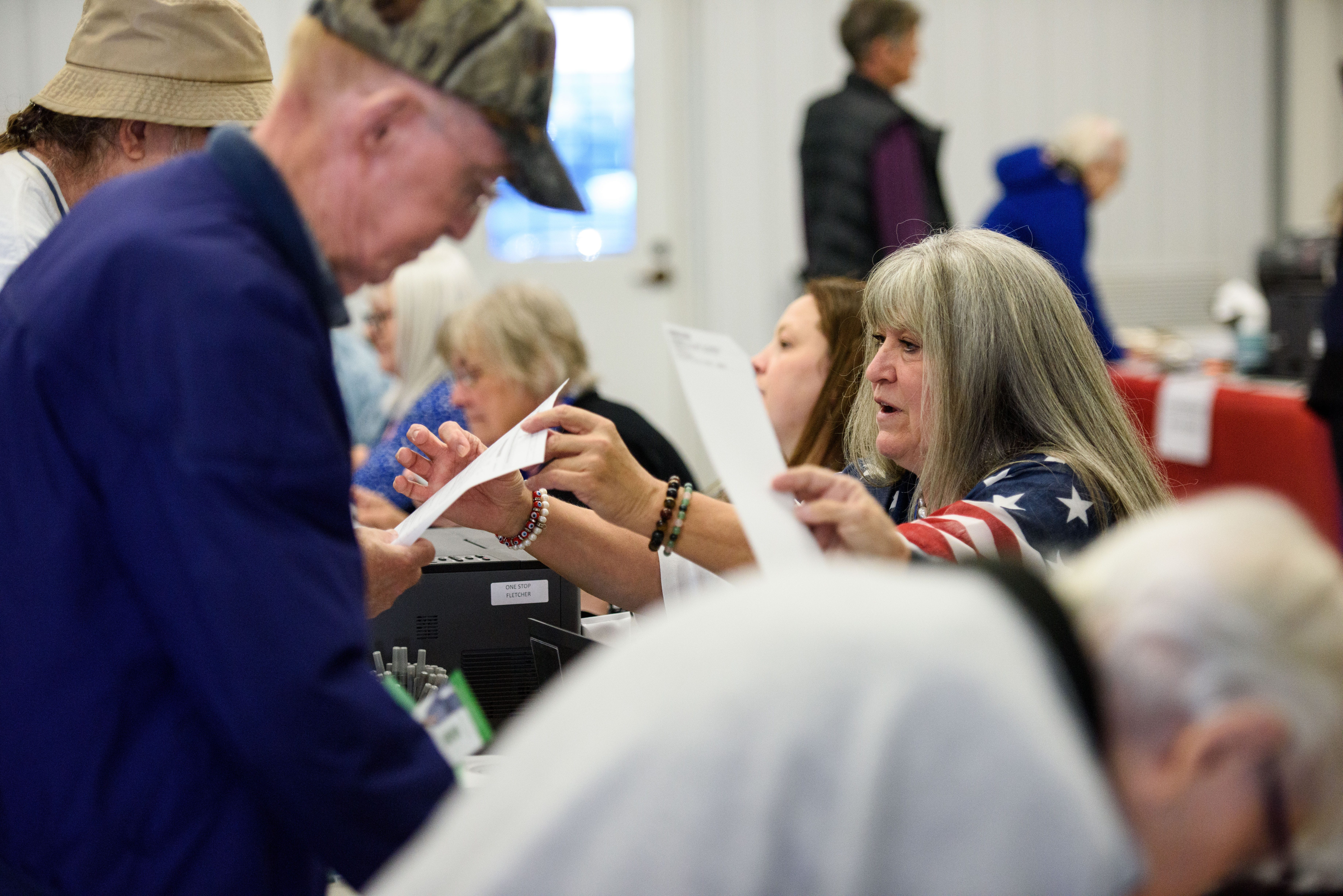 HENDERSONVILLE, NORTH CAROLINA - OCTOBER 17: Poll workers assist voters as they check in for early voting and receive ballots on October 17, 2024 in Hendersonville, North Carolina. Several counties effected by Hurricane Helene saw a large turnout of residents for the first day of early voting in Western North Carolina. (Photo by Melissa Sue Gerrits/Getty Images)
