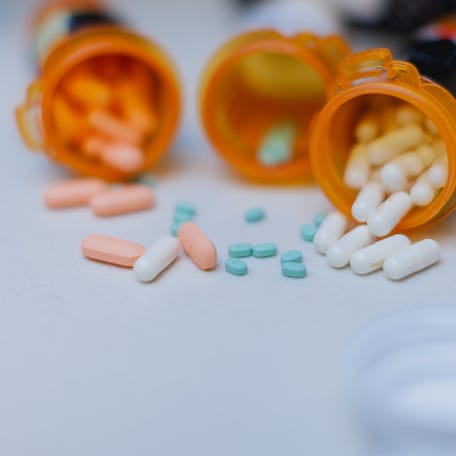 Part of daily life routine for an adult with ADHD, taking the right medication that helps them focus on daily life and achieve their goals throughout the day. These ADHD pills and other medicines are displayed with open pill bottles on top of a white counter top in the kitchen.