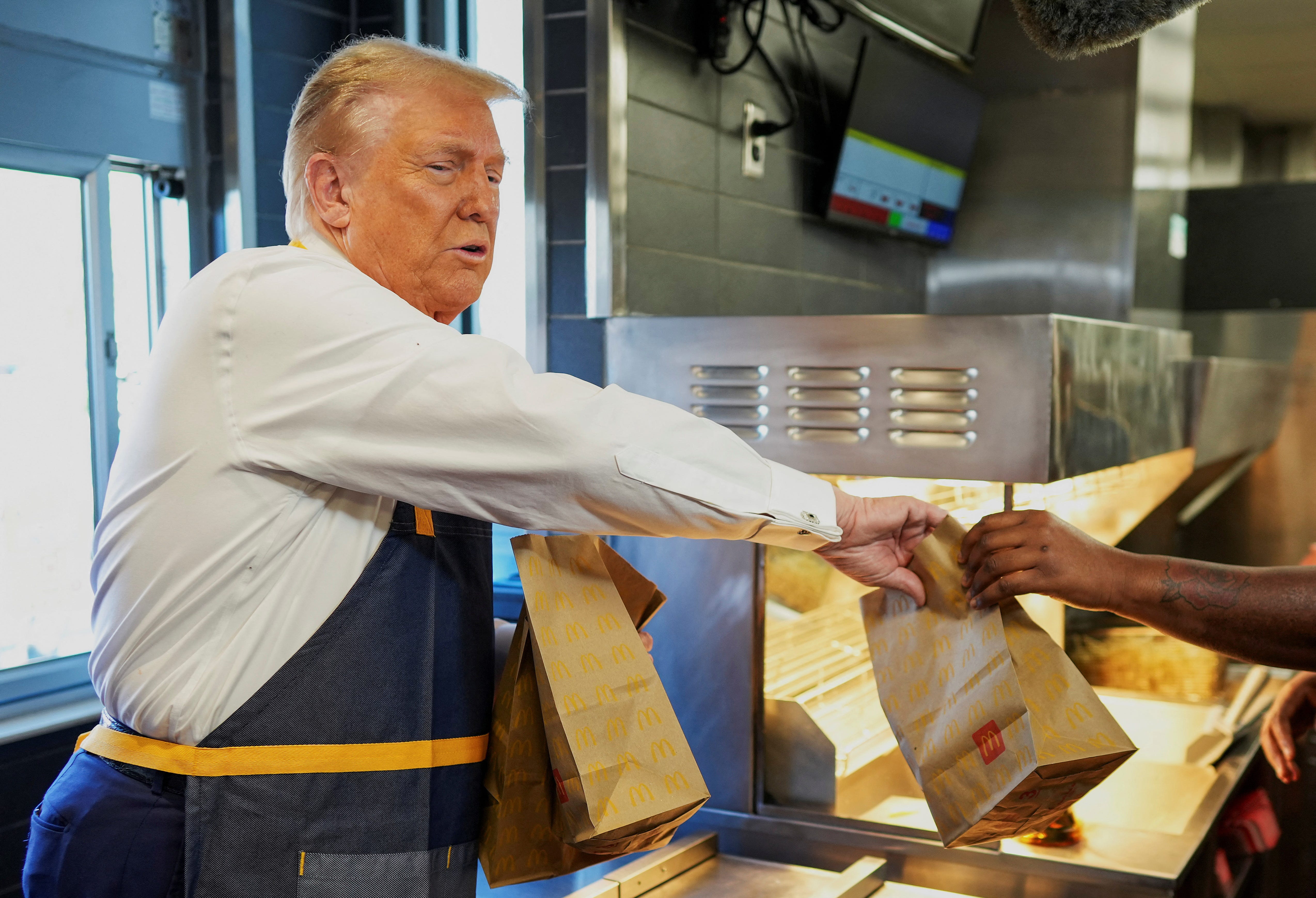 Republican presidential nominee and former U.S. President Donald Trump works behind the counter during a visit to McDonalds in Feasterville-Trevose, Pennsylvania, U.S. October 20, 2024.