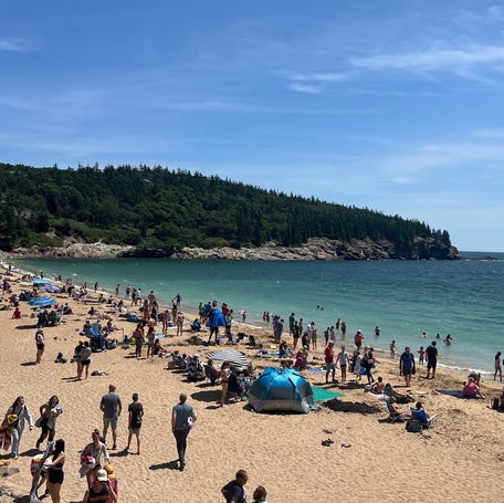 Visitor enjoy a sunny summer day at Acadia National Park's Sand Beach.