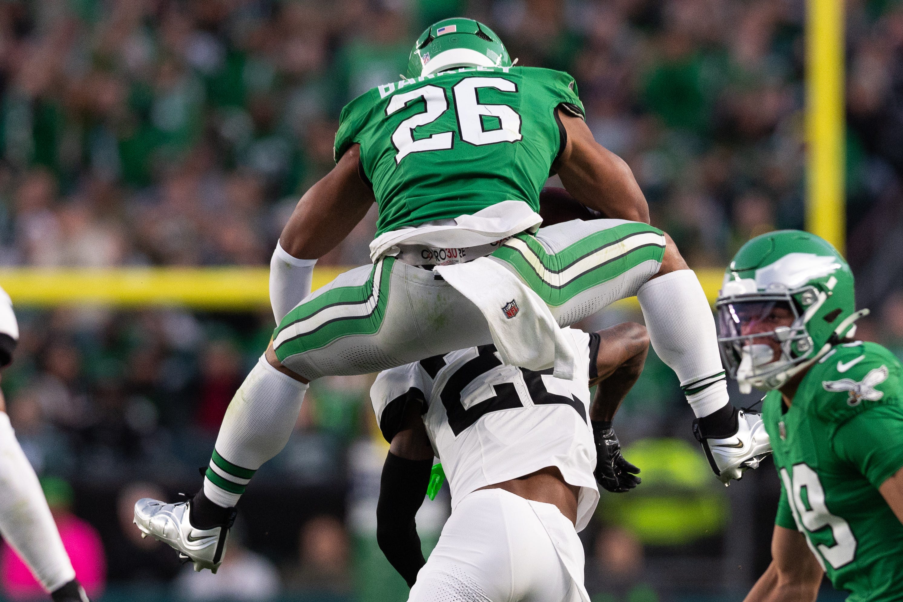 Philadelphia Eagles running back Saquon Barkley (26) leaps with the ball over Jacksonville Jaguars cornerback Jarrian Jones (22) during the second quarter at Lincoln Financial Field. Mandatory Credit: Bill Streicher-Imagn Images