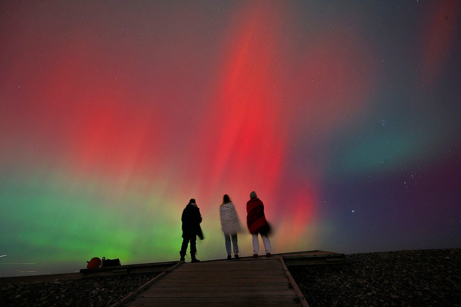 Stunning northern lights display with green and red hues in the night sky.