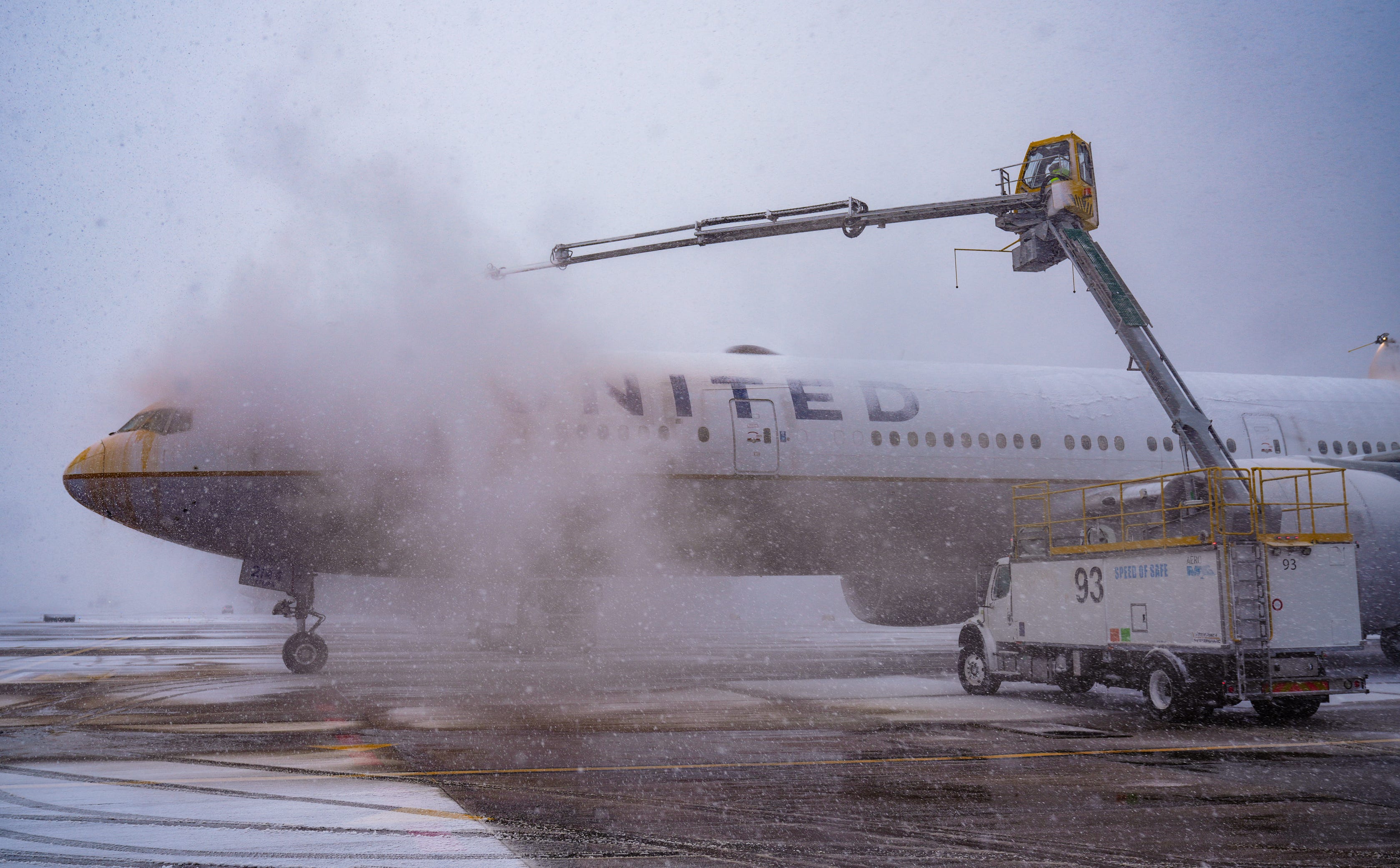 Worker spray deicing fluid on an airplane at Denver International Airport on Wednesday, Nov. 27, 2024, during a snowstorm.