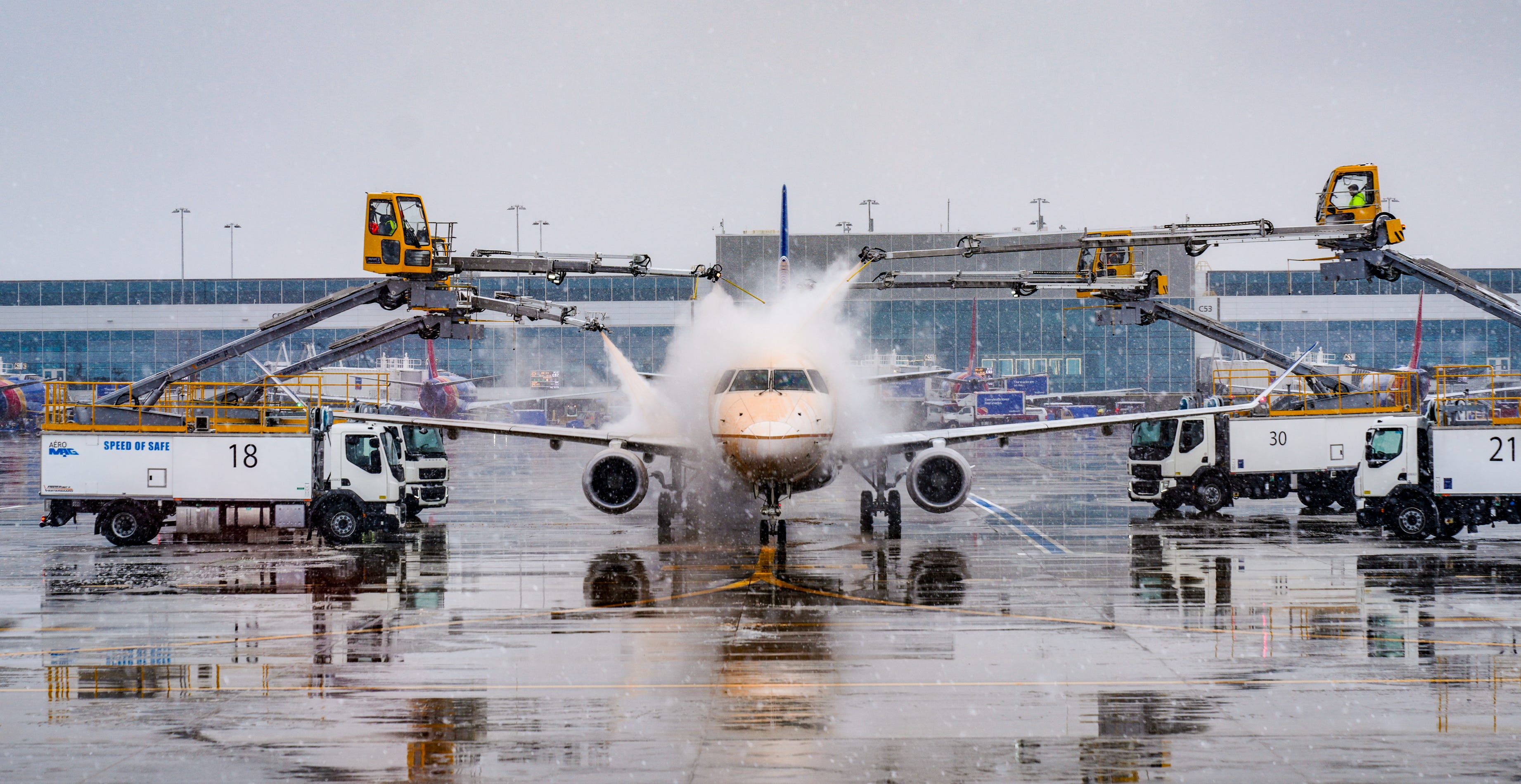 Workers spray deicing fluid on an airplane at Denver International Airport on Wednesday, Nov. 27, 2024, during a snowstorm. The deicing fluid sticks to surfaces so that snow and ice can't build up when airplanes are waiting to take off in snowy conditions.
