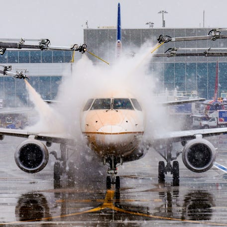 Workers spray deicing fluid on an airplane at Denver International Airport on Wednesday, Nov. 27, 2024, during a snowstorm. The deicing fluid sticks to surfaces so that snow and ice can't build up when airplanes are waiting to take off in snowy conditions.