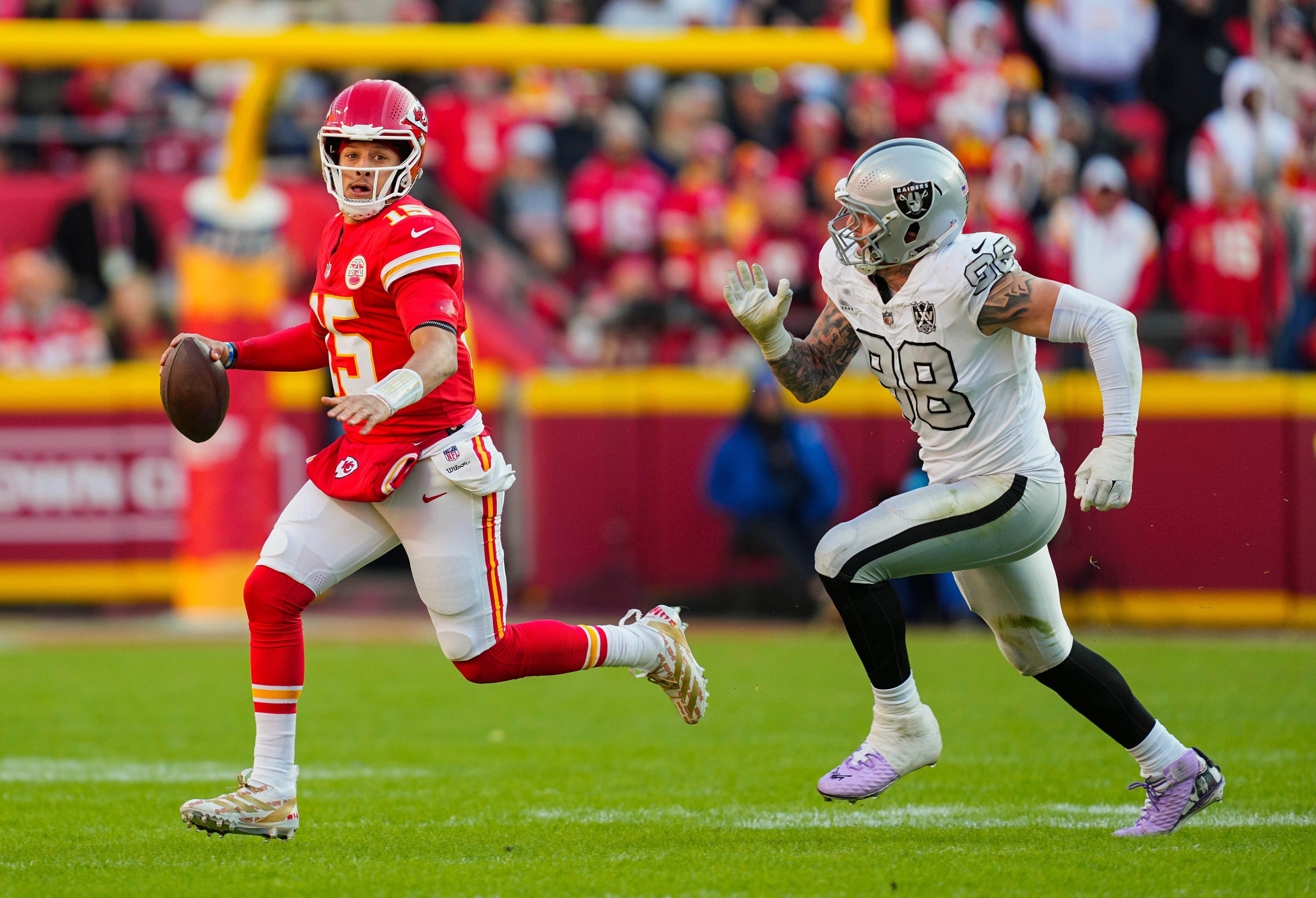 Nov 29, 2024; Kansas City, Missouri, USA; Kansas City Chiefs quarterback Patrick Mahomes (15) scrambles from Las Vegas Raiders defensive end Maxx Crosby (98) during the first half at GEHA Field at Arrowhead Stadium. Mandatory Credit: Jay Biggerstaff-Imagn Images
