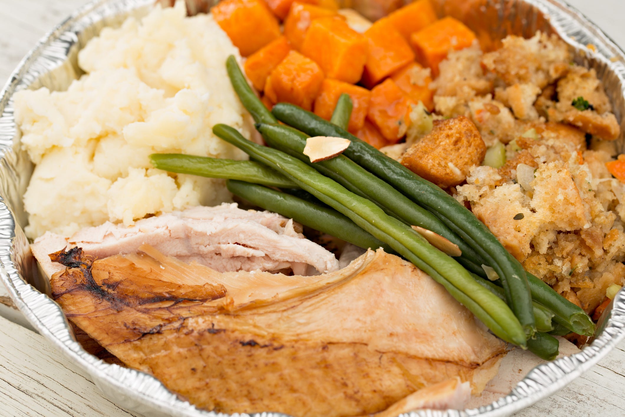 Thanksgiving Day dinner leftovers sit in a pie-sized aluminum container.
