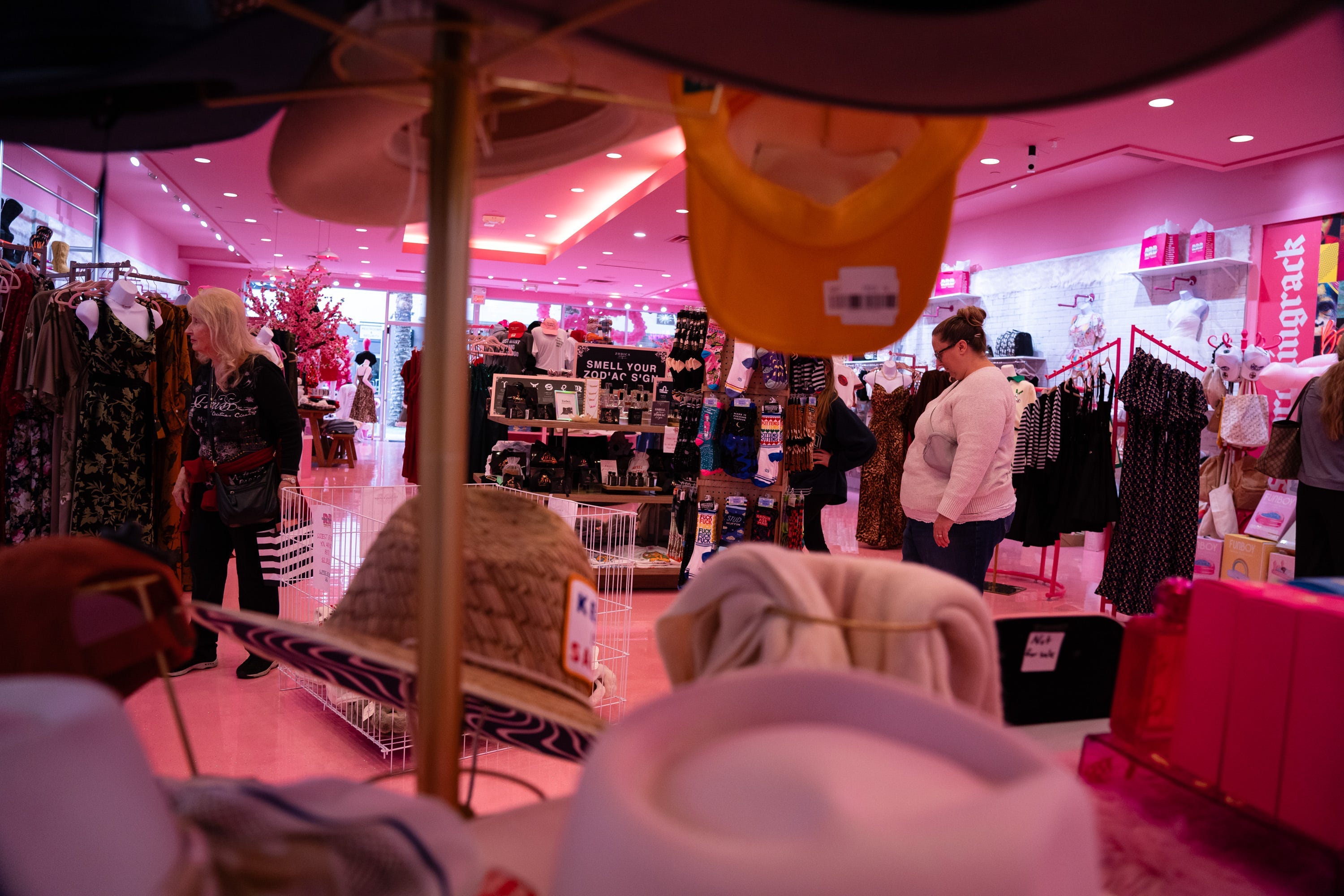 Seen past a hat rack, people shop at Rolling Rack Boutique at Desert Ridge Marketplace on Black Friday on Nov. 29, 2024, in Phoenix.