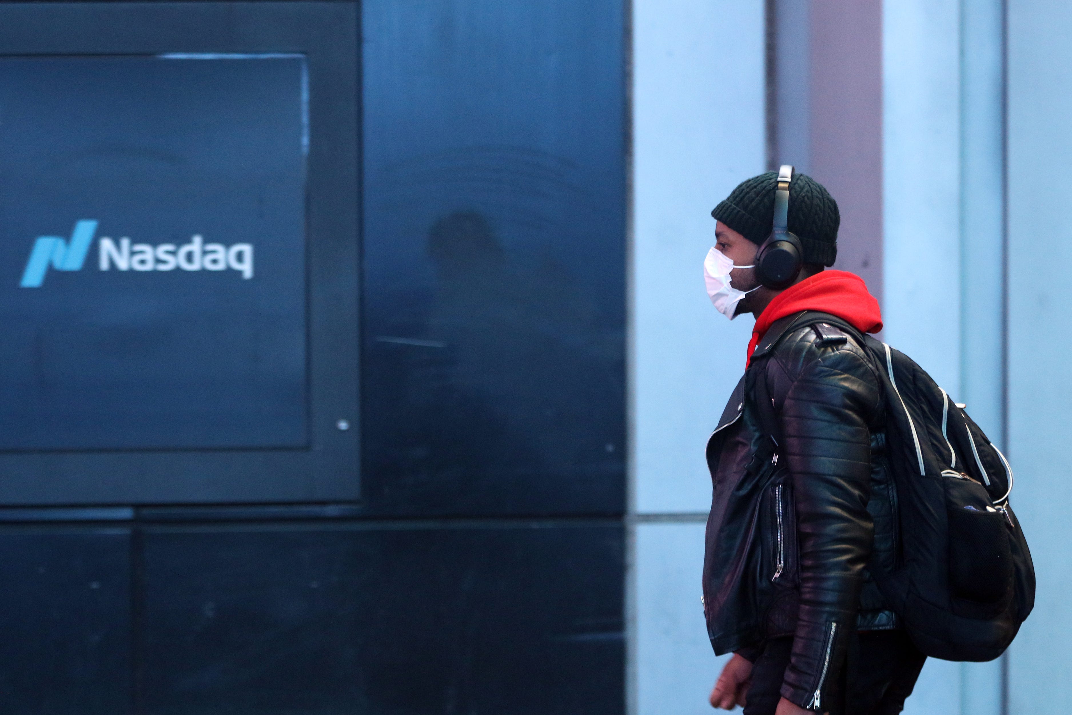 A man walks by a Nasdaq sign in Times Square in March 2020