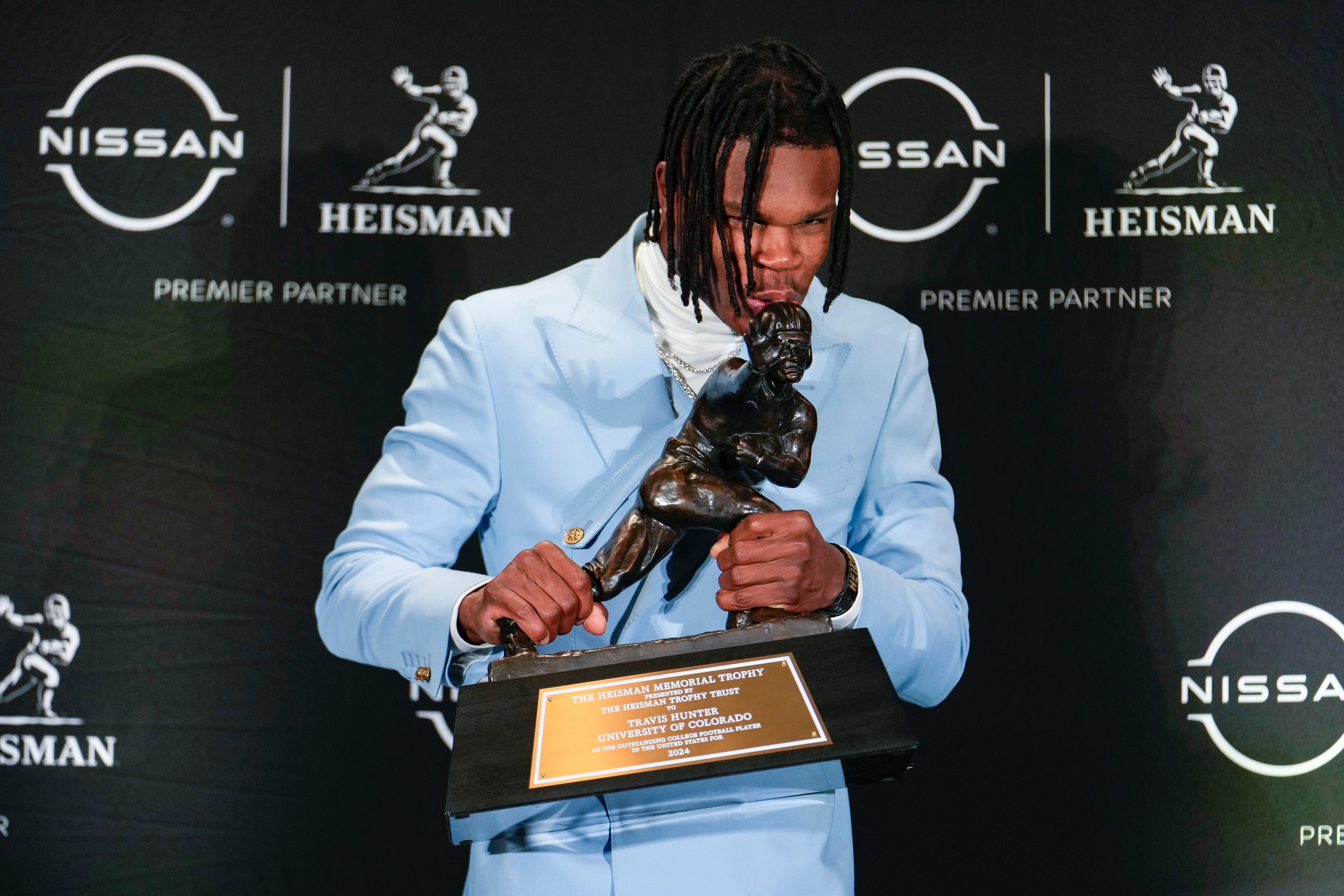 Colorado's Travis Hunter kisses the Heisman Trophy.