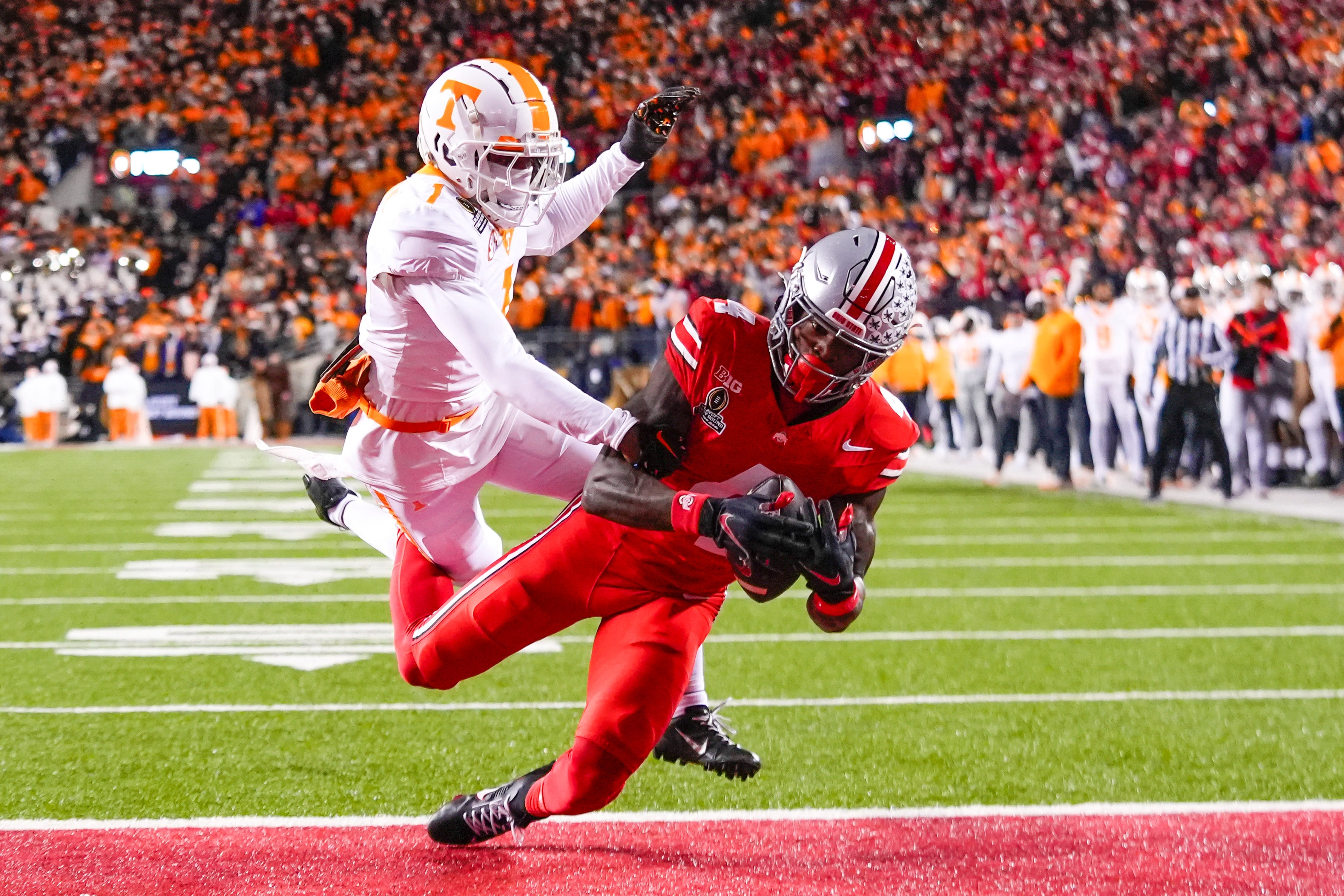 Ohio State wide receiver Jeremiah Smith (4) catches a touchdown pass as Tennessee defensive back Rickey Gibson III (1) defends during the first half of their College Football Playoff game at Ohio Stadium on Saturday, Dec. 21, 2024 in Columbus, Ohio.