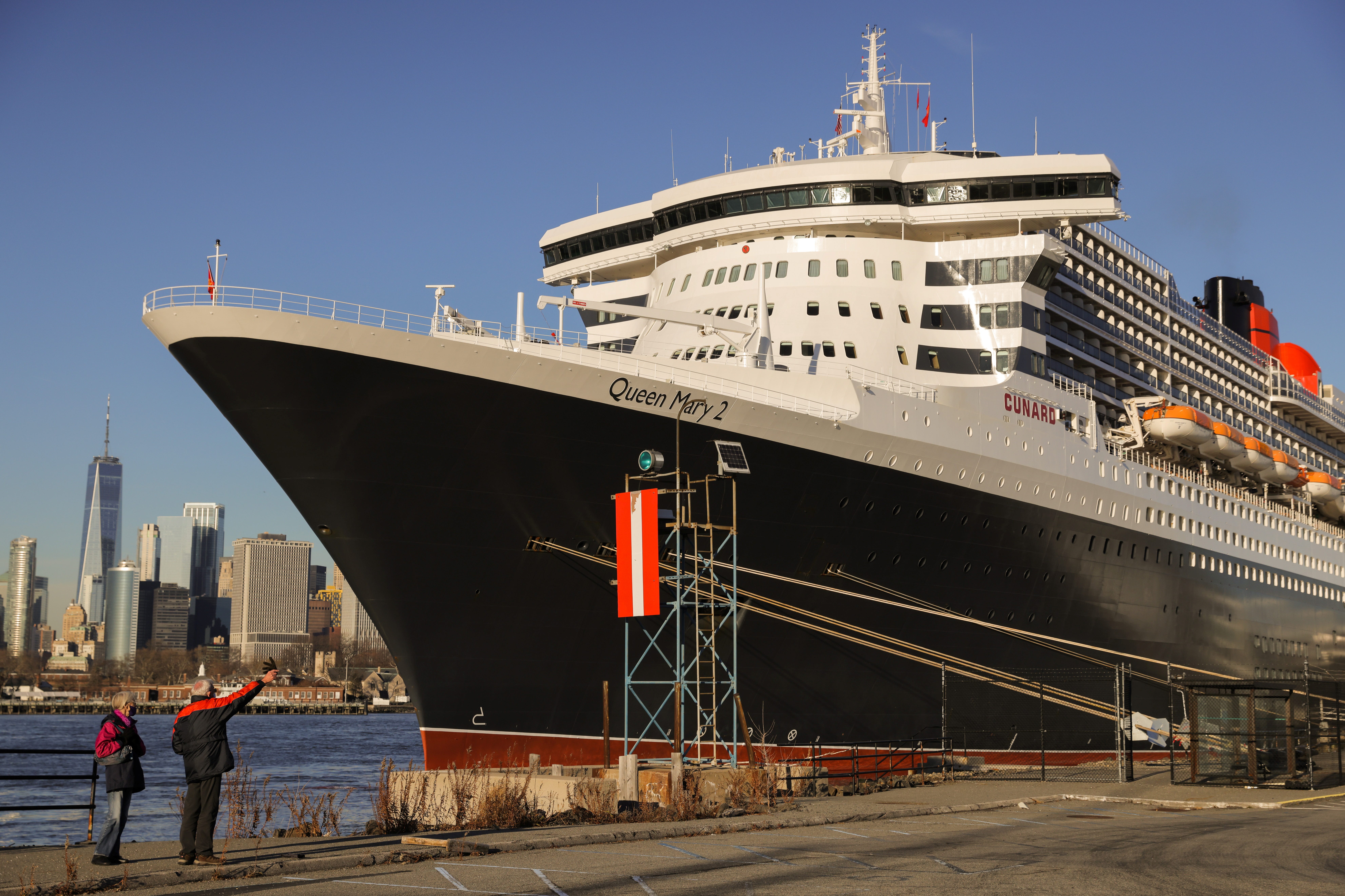 People look toward Cunard Line's Queen Mary 2 ship as it sits docked in Brooklyn, New York City, on Dec. 20, 2021.