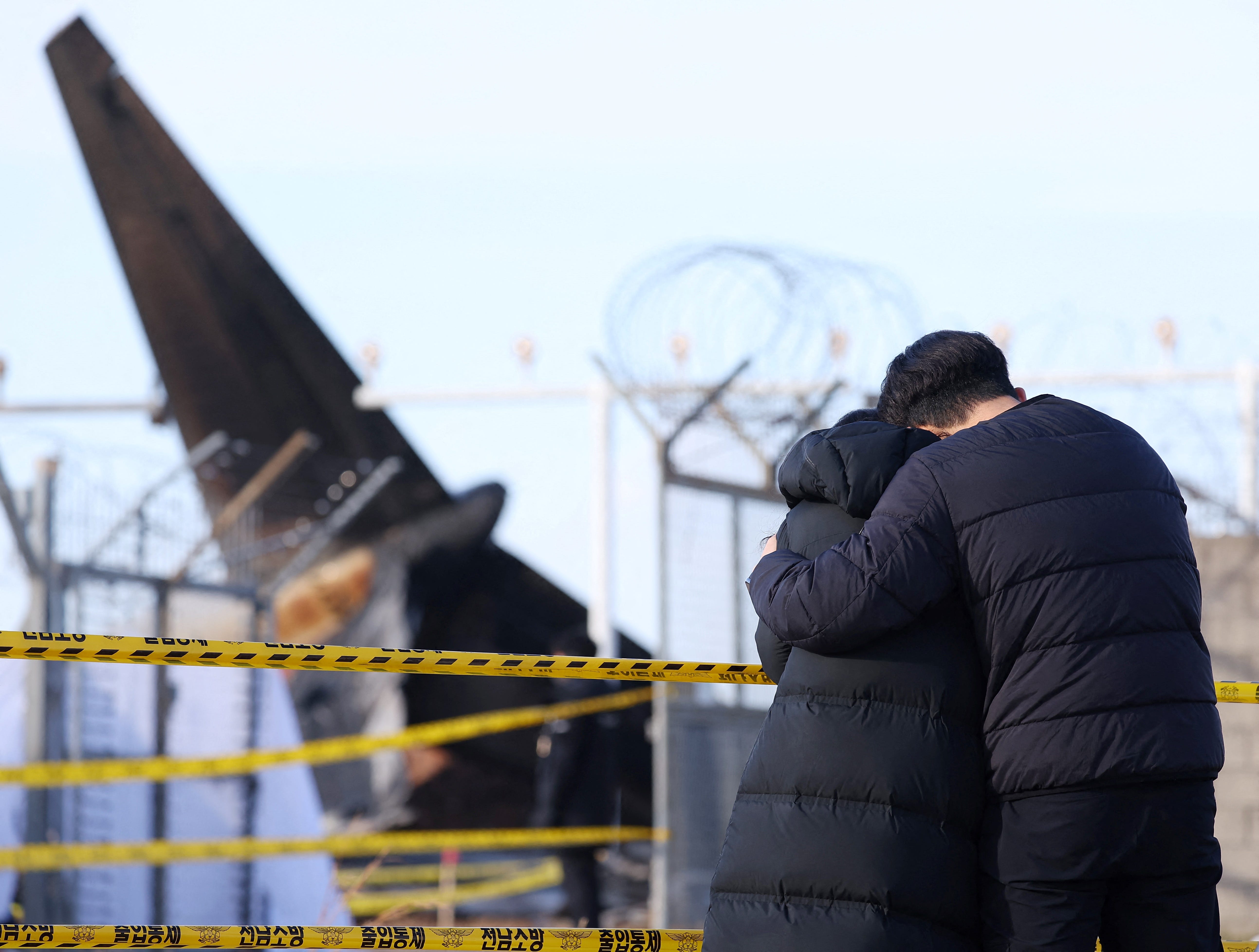 Bereaved family members stand at the scene where a Jeju Air Boeing 737-800 series aircraft crashed and burst into flames at Muan International Airport in Muan, some 288 kilometers southwest of Seoul on December 30, 2024. The Boeing 737-800 was carrying 181 people from Thailand to South Korea when it crashed on arrival on December 29, killing everyone aboard -- save two flight attendants pulled from the twisted wreckage of the worst aviation disaster on South Korean   soil.