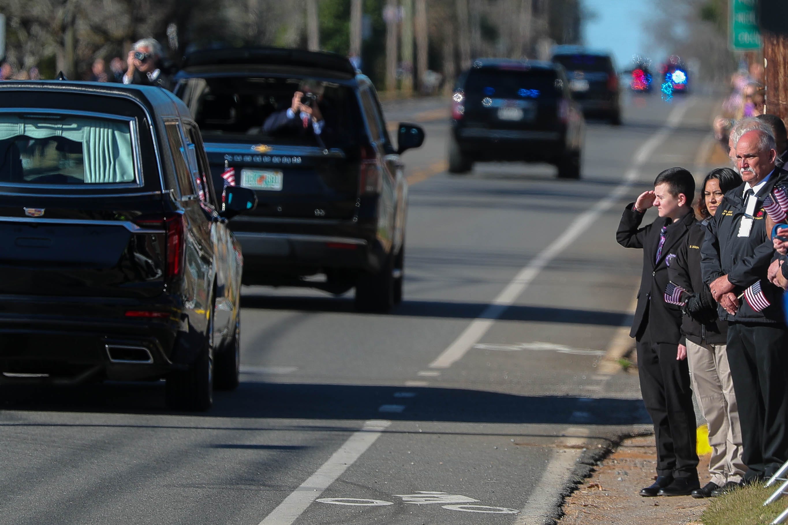 A boy salutes as the hearse carrying former President Jimmy Carter travels along Church Street through Plains, Georgia on Saturday, Jan. 4, 2025.