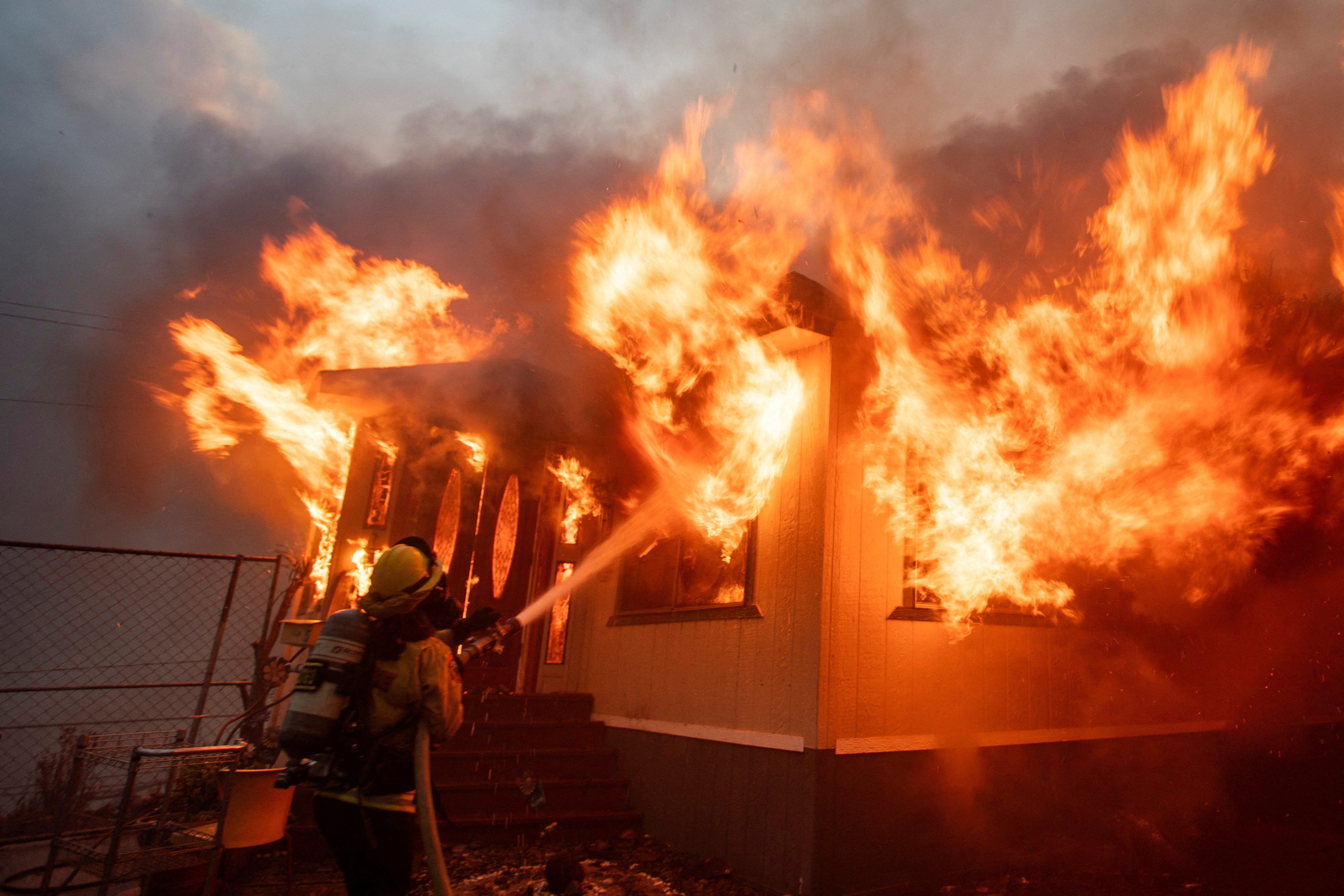 A firefighter battles the Palisades Fire as it burns during a windstorm on the west side of Los Angeles on January 7, 2025.